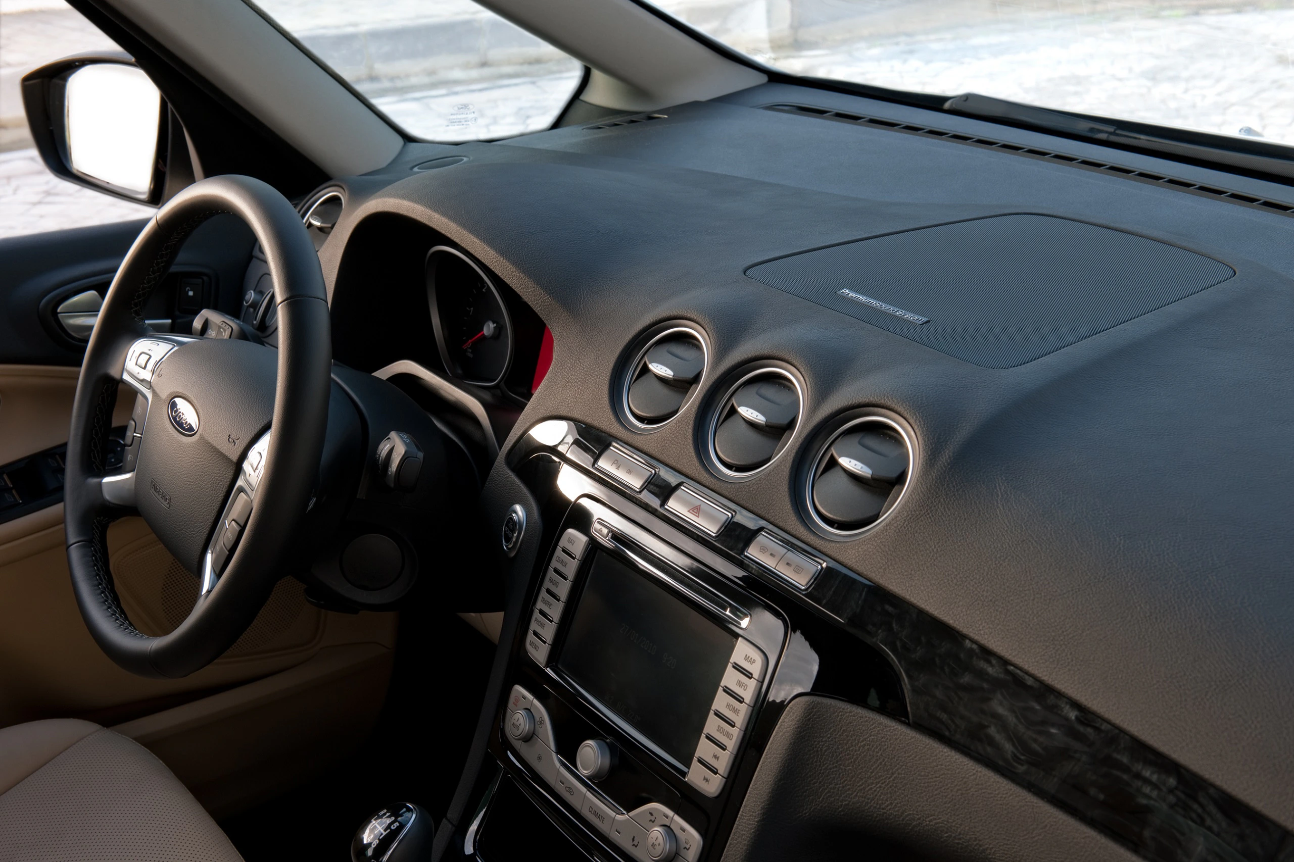 Innenraum eines Autos mit Ledersitzen, Multifunktionslenkrad, Touchscreen-Display und runden Lüftungsdüsen.