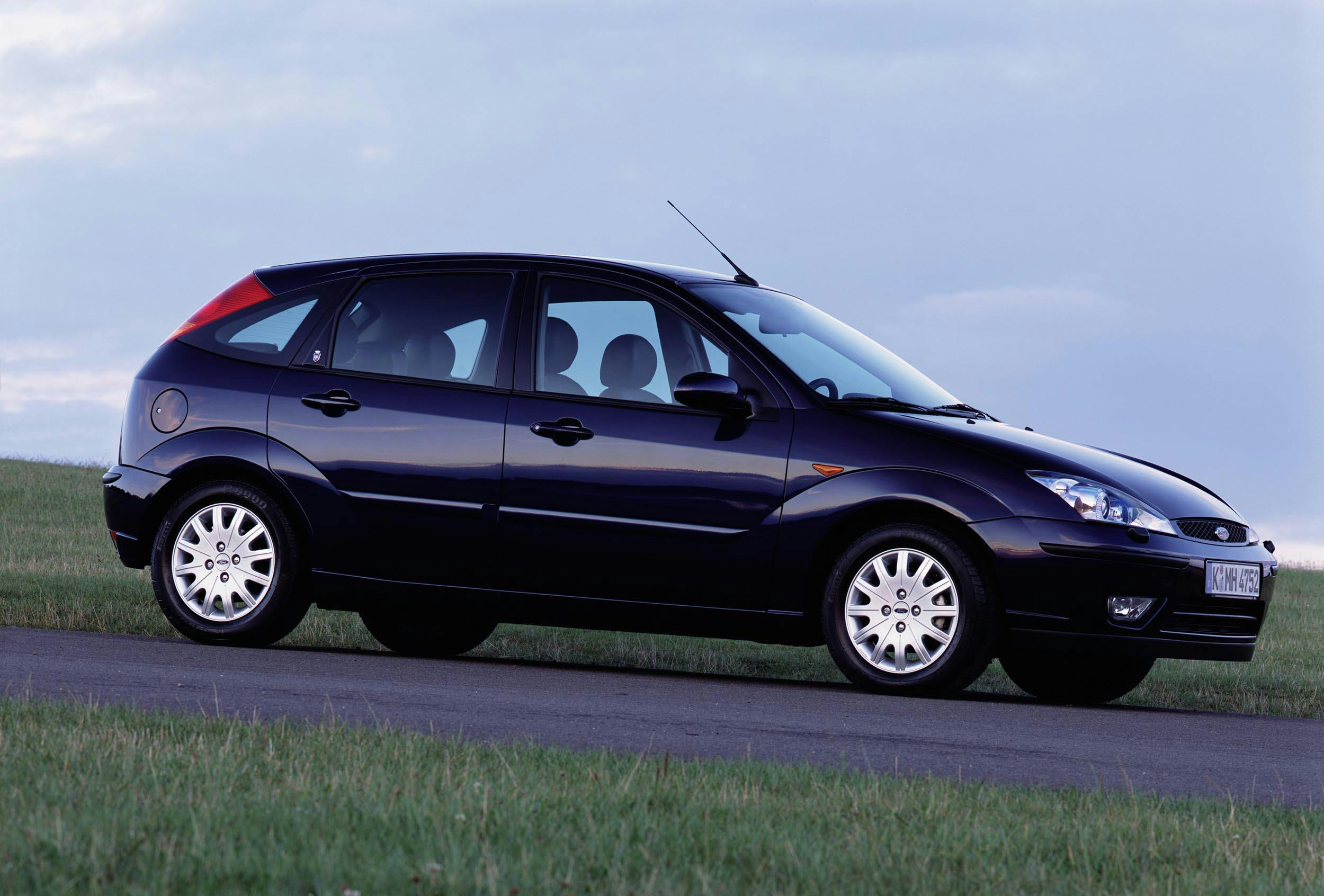 Schwarzer Ford Focus der frühen 2000er auf einer Landstraße vor blauem Himmel, seitlich fotografiert.
