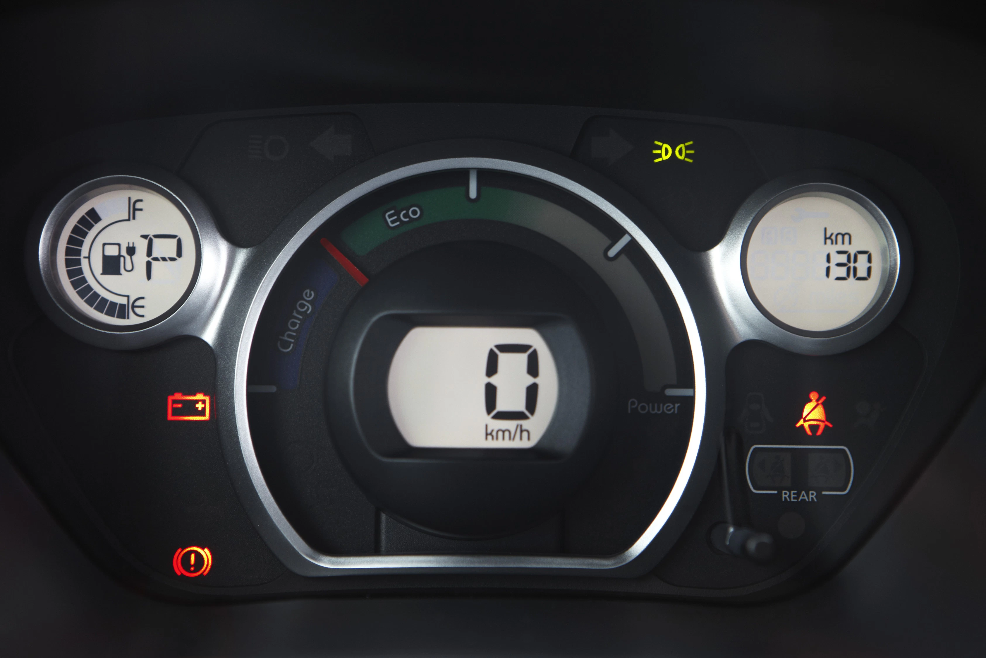 Nahaufnahme eines Auto-Tachometers mit digitaler Geschwindigkeitsanzeige bei 0 km/h und verschiedenen leuchtenden Kontrollleuchten.