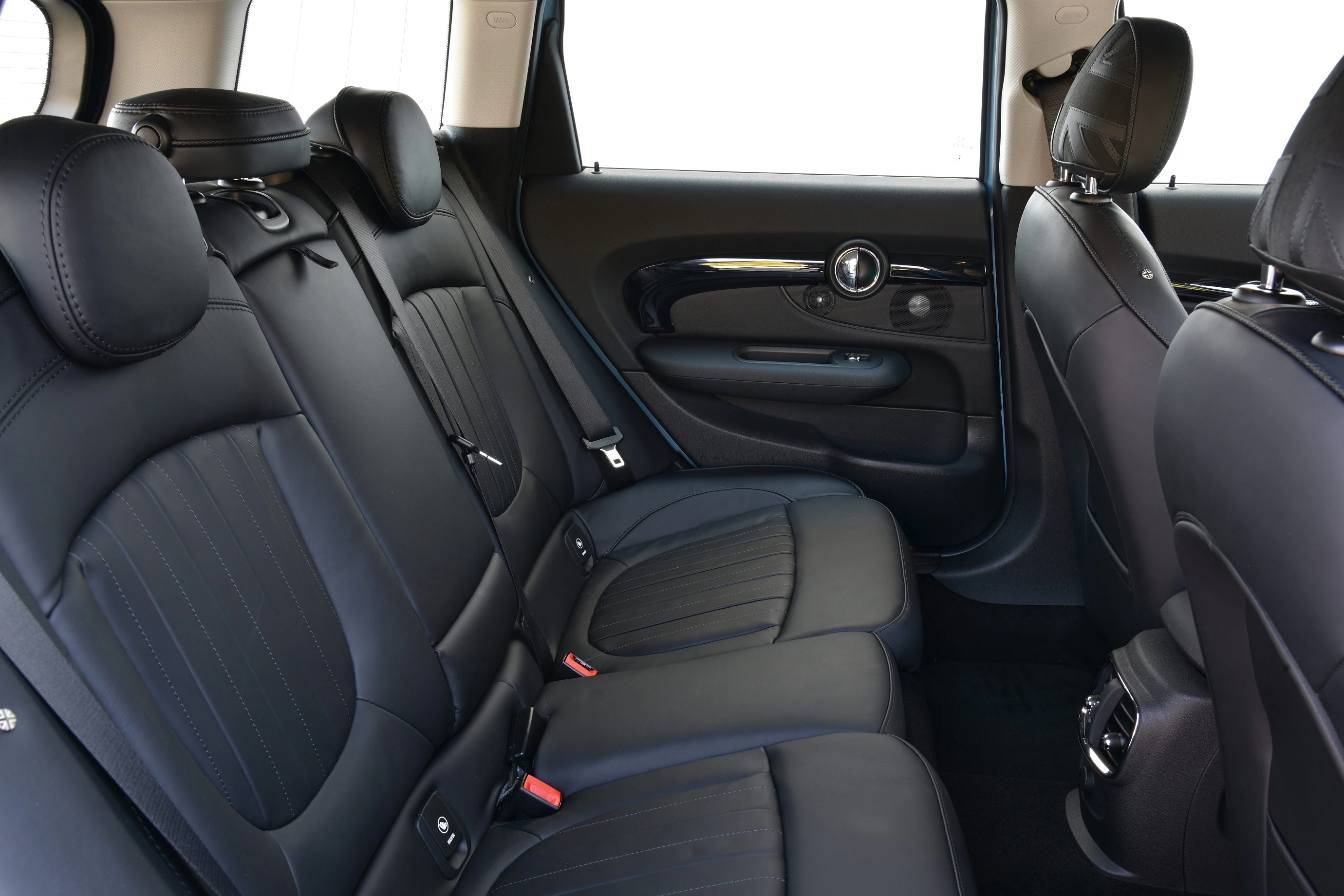 Rückbank eines Autos mit eleganten schwarzen Ledersitzen, zwei Kopfstützen und modernem Interieur. Fenster und Türverkleidung sichtbar.