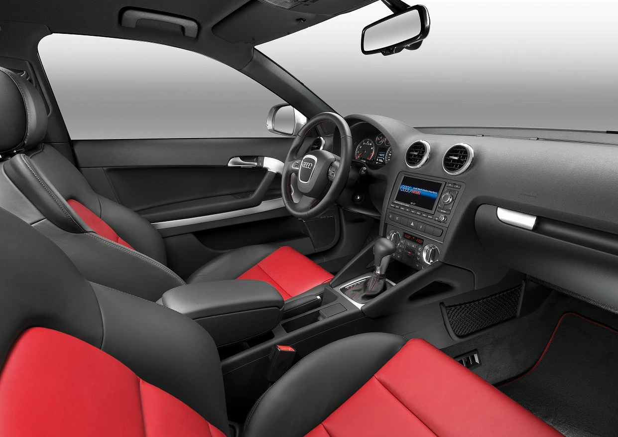 Innenraum eines Autos mit schwarzem Armaturenbrett und Lenkrad, schwarzen und roten Ledersitzen. Modernes Design mit Multimedia-System.