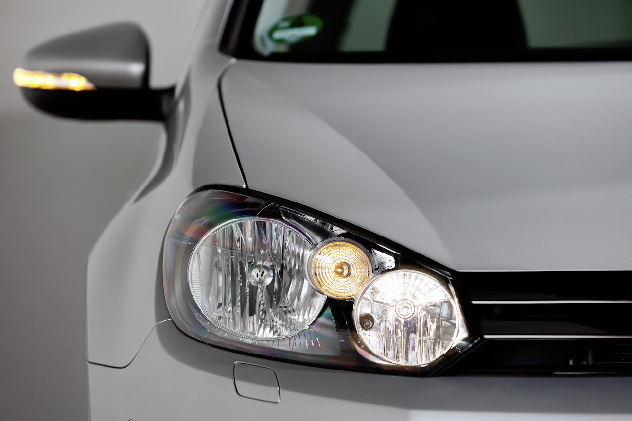 Nahaufnahme eines silbernen Autoscheinwerfers und Seitenspiegels, modernes Design mit klaren Linien und Details.