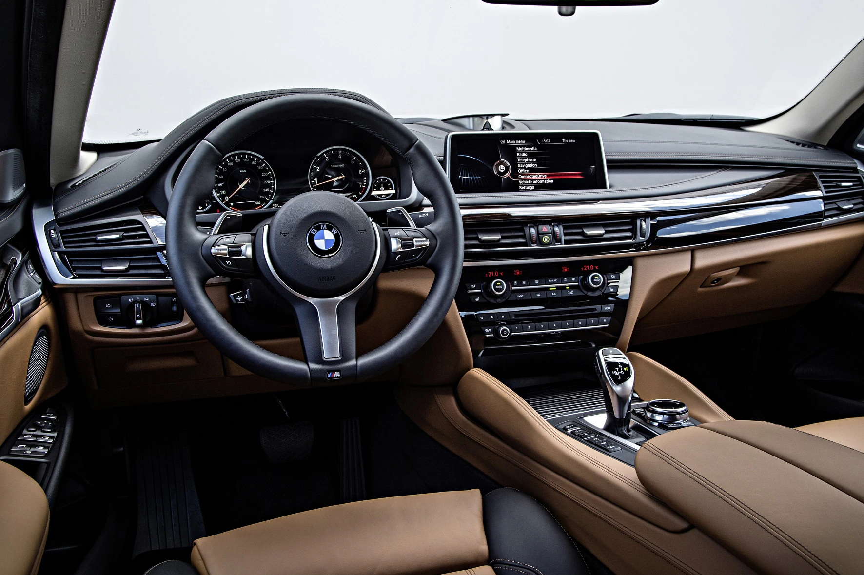 Innenraum eines BMWs mit luxuriösem Design: Lederverkleidung, großes Display, modernes Lenkrad und zahlreiche Bedienelemente.