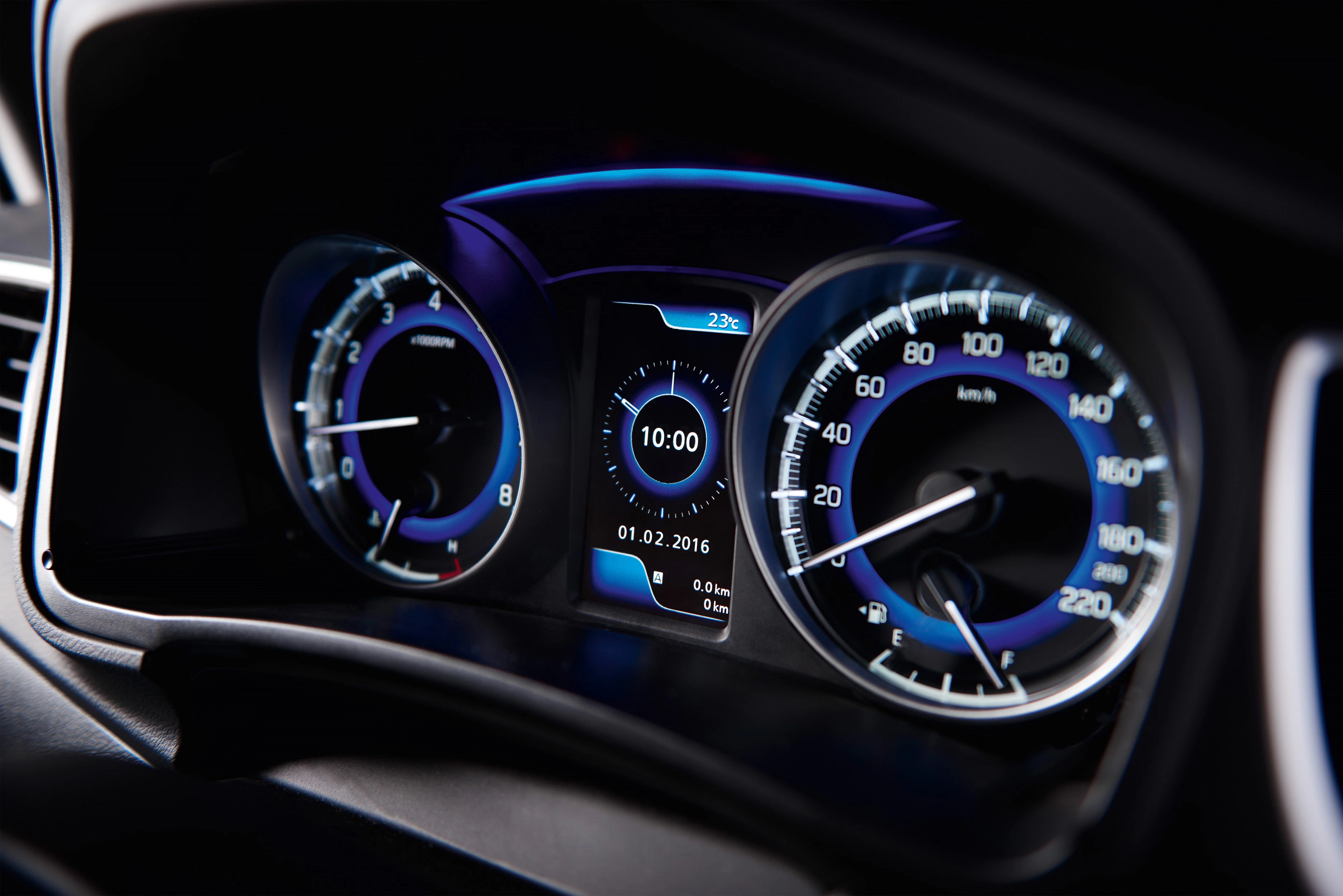 Nahaufnahme eines beleuchteten Auto-Tachometers mit Tachometer und digitaler Anzeige in der Mitte, die das Datum und die Uhrzeit zeigt.
