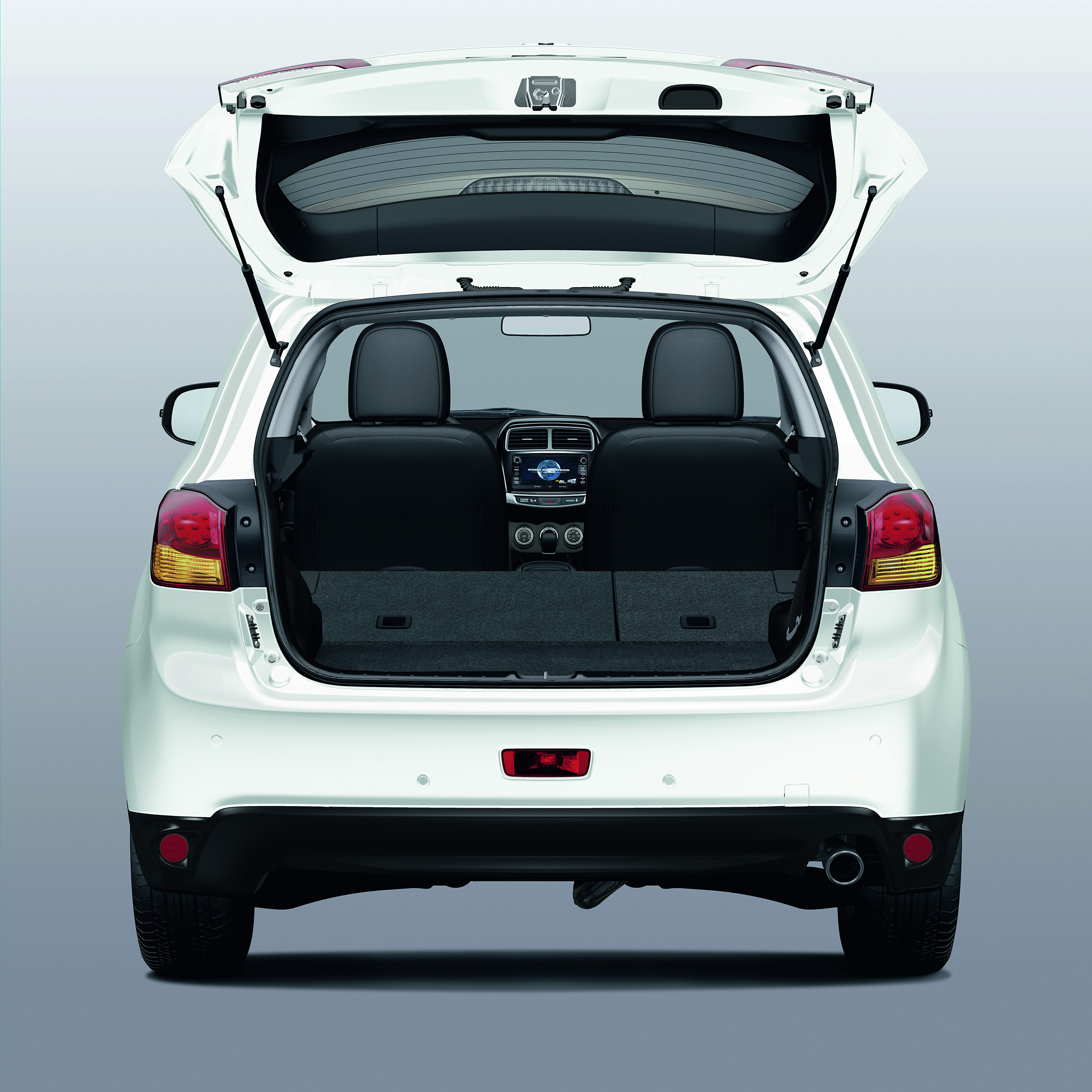 Weiße Limousine mit geöffneter Heckklappe, die den Innenraum und die Rücksitze zeigt. Hintergrund ist einfarbig hellgrau.