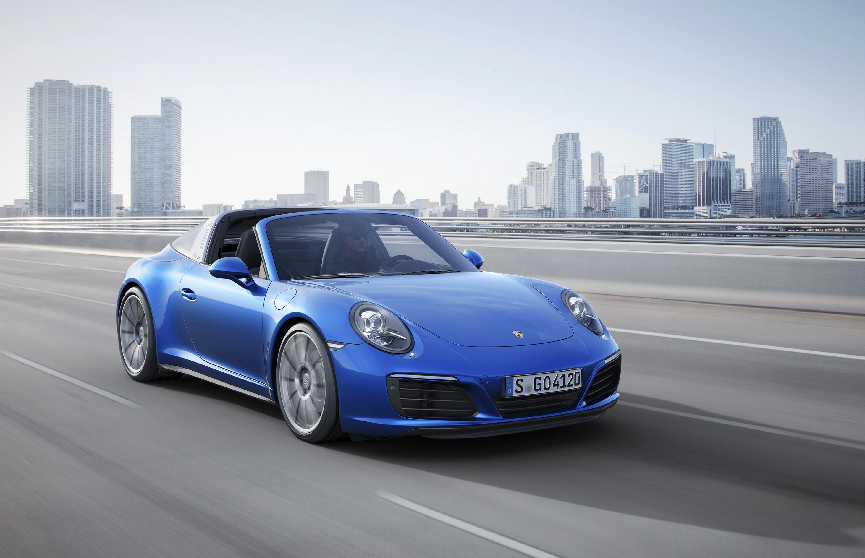 Blauer Sportwagen fährt auf einer Autobahn mit einer modernen Stadt und Wolkenkratzern im Hintergrund.