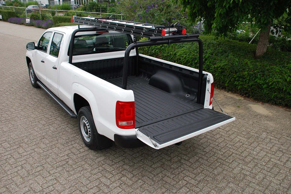 Großer weißer Pickup mit heruntergeklappter Heckklappe und Leiter auf Dachträger, auf einem gepflasterten Weg geparkt.