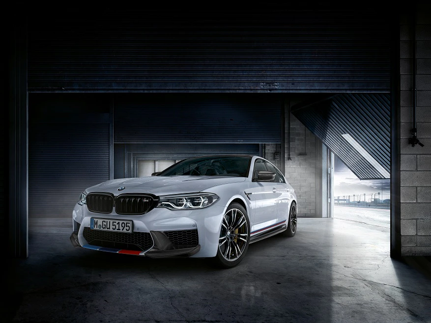 Ein weißer Sportwagen steht in einer Garage mit offenen Toren, umgeben von modernem industriellen Design.