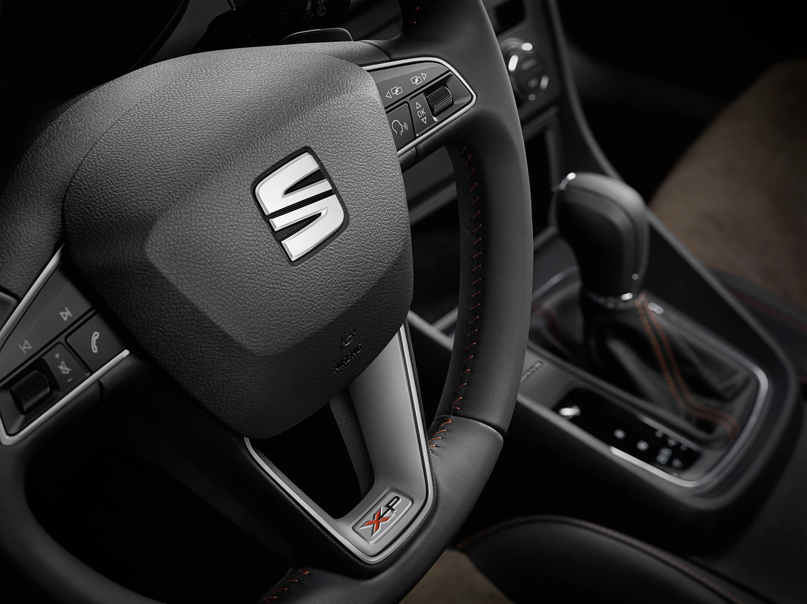 Nahaufnahme eines Lenkrads mit dem SEAT-Logo und einem Automatikschalthebel in einem modernen Auto-Innenraum.
