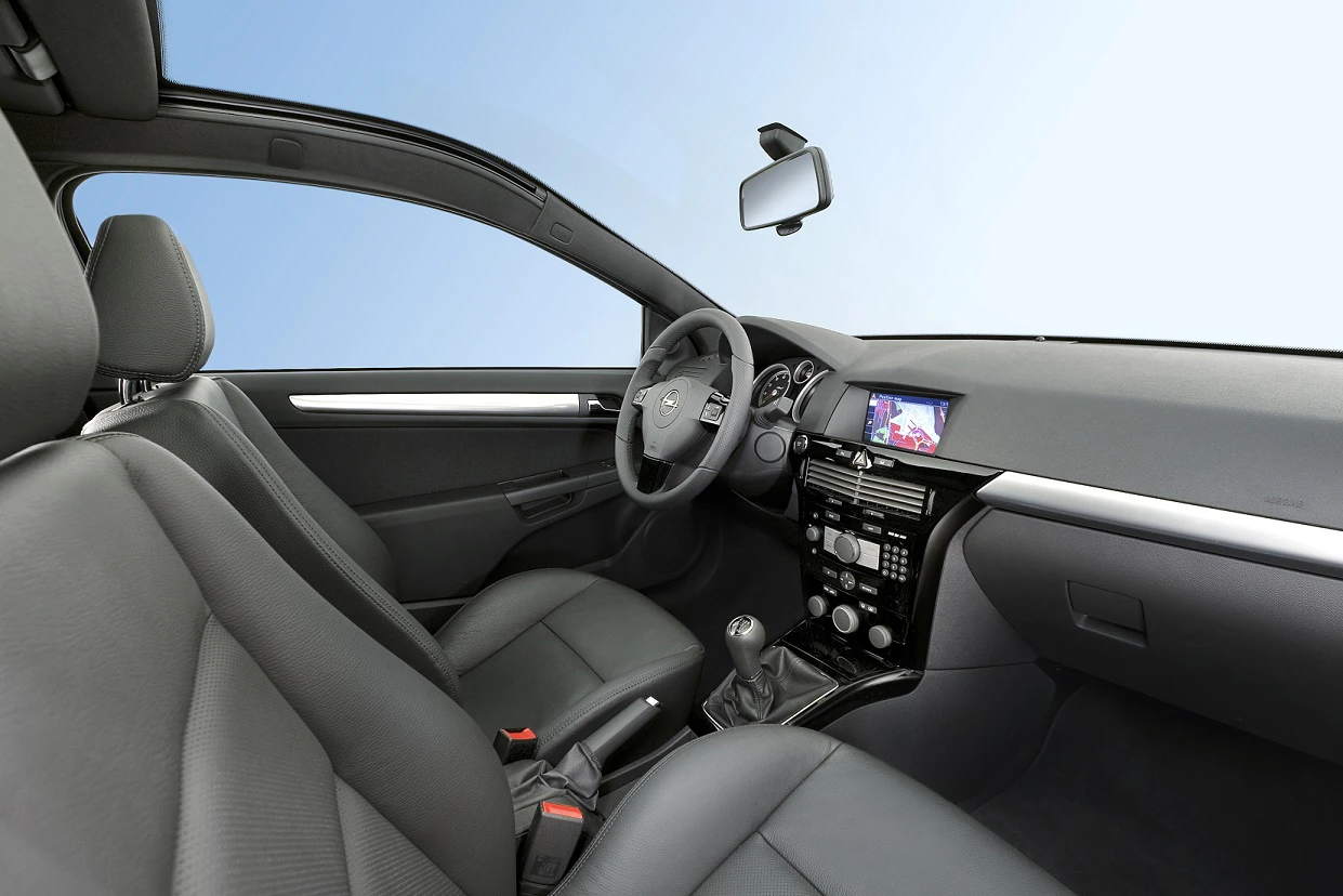 Innenraum eines modernen Autos mit schwarzen Ledersitzen und einem Armaturenbrett mit Navigationssystem und Schaltgetriebe vor blauem Hintergrund.