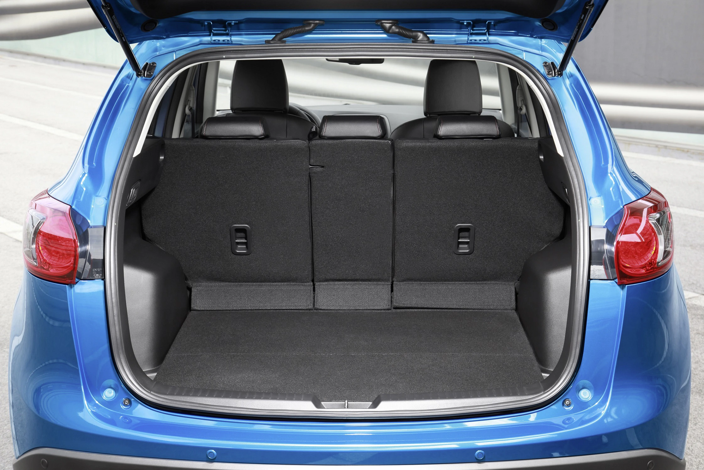 Blauer SUV mit geöffneter Heckklappe, zeigt einen leeren, geräumigen Kofferraum. Rücksitze können umgeklappt werden.