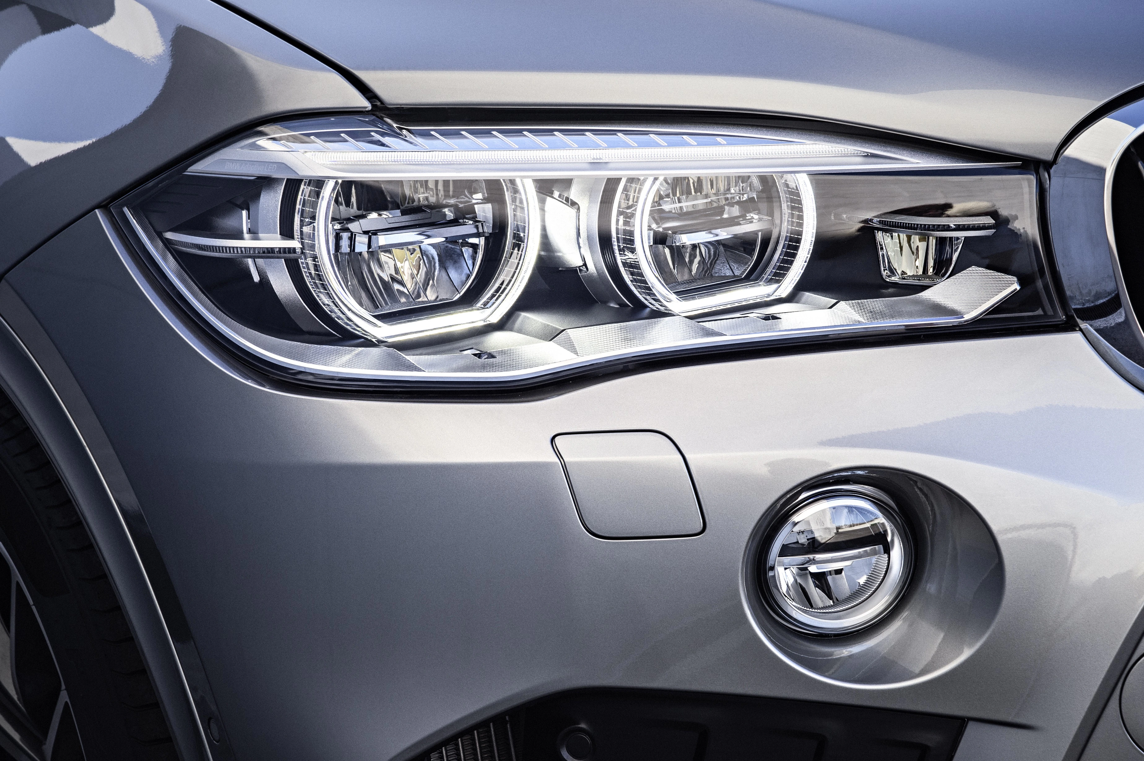Nahaufnahme eines Autoscheinwerfers eines modernen Fahrzeugs in silberner Farbe, mit mehreren Lichtringen und eleganten Konturen.