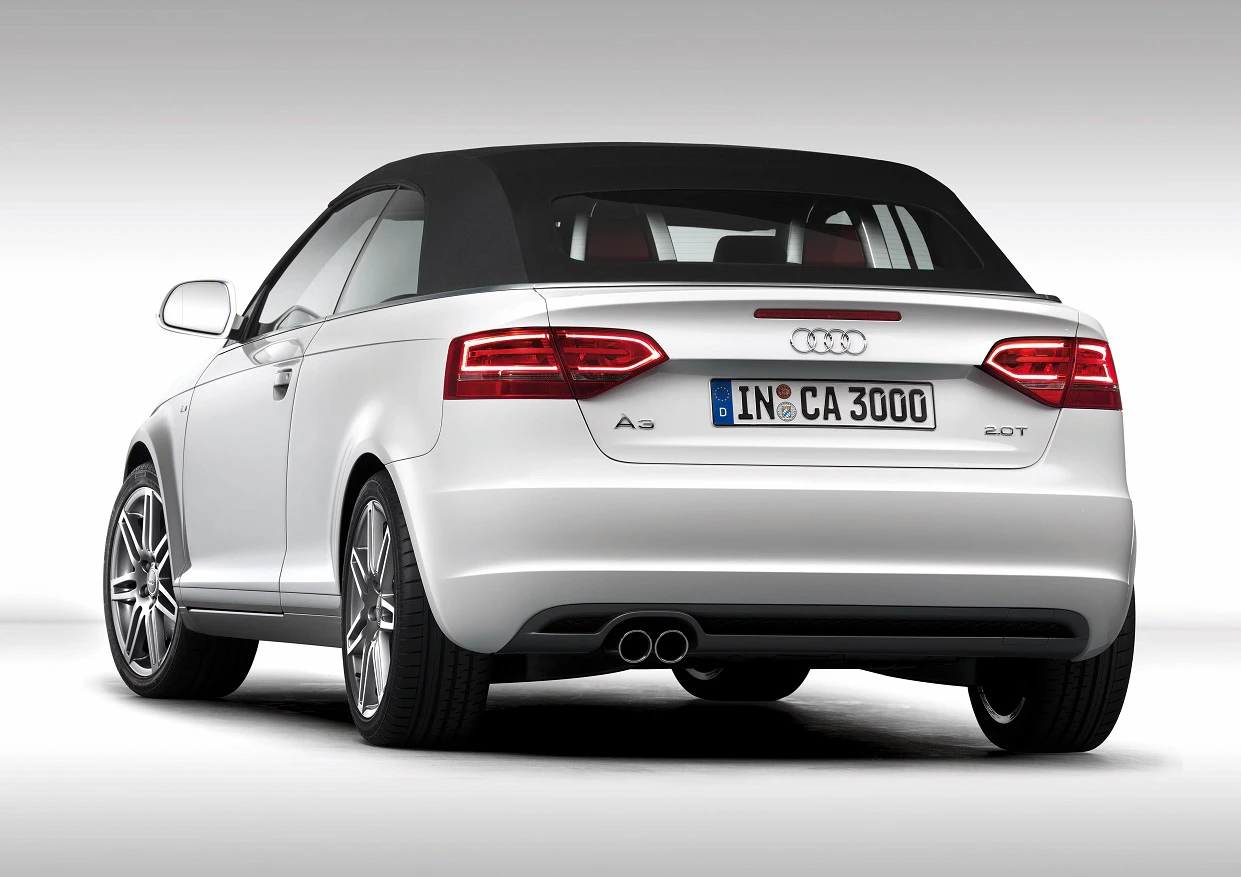 Silberner Audi A3 Cabriolet, Heckansicht. Schwarzes Dach, Doppelauspuff, Rücklichter eingeschaltet. Nummernschild: IN-CA 3000.