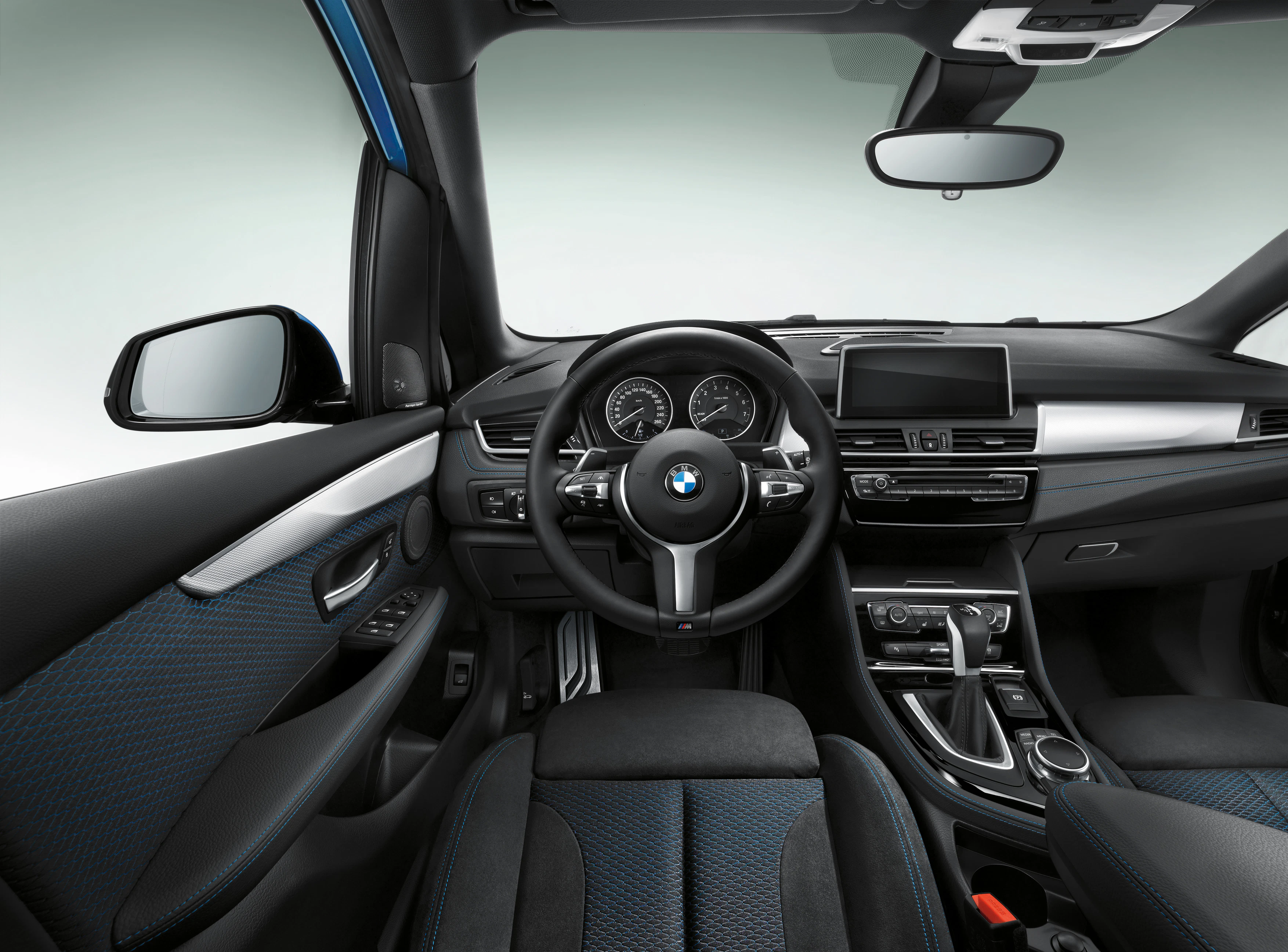 Innenraum eines modernen Autos mit grauen und blauen Sitzen, Multifunktionslenkrad und zentralem Bildschirm im Armaturenbrett.