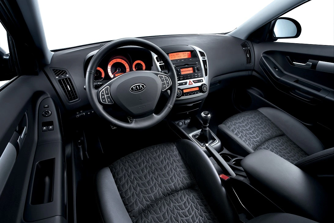 Innenansicht eines modernen Autos mit schwarzem Interieur, beleuchtetem Armaturenbrett und Ledersitzen.