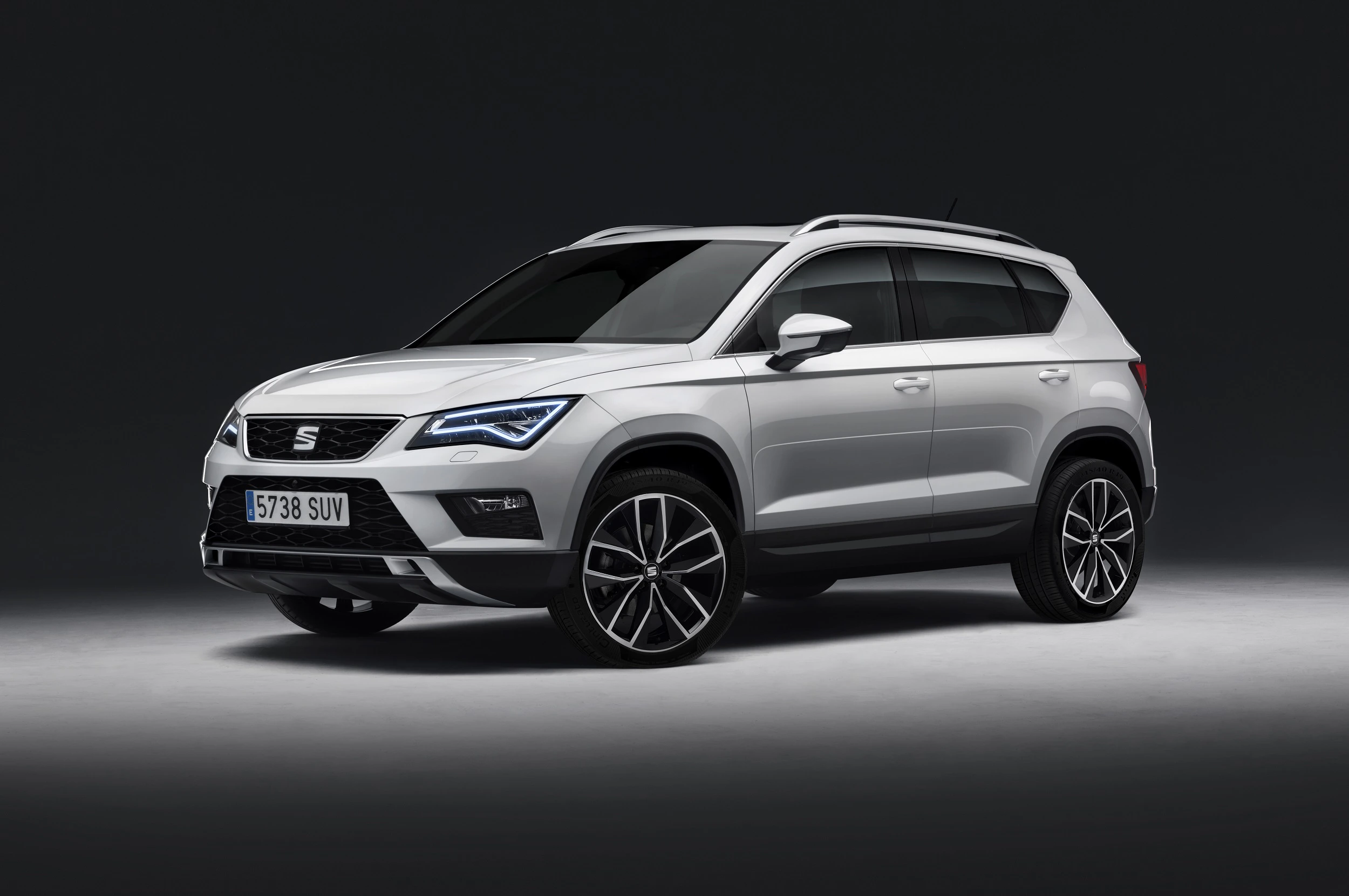 Weißer SUV der Marke SEAT von der Seite auf grauem Hintergrund. Elegantes Design mit dunklen Felgen und moderner LED-Beleuchtung.
