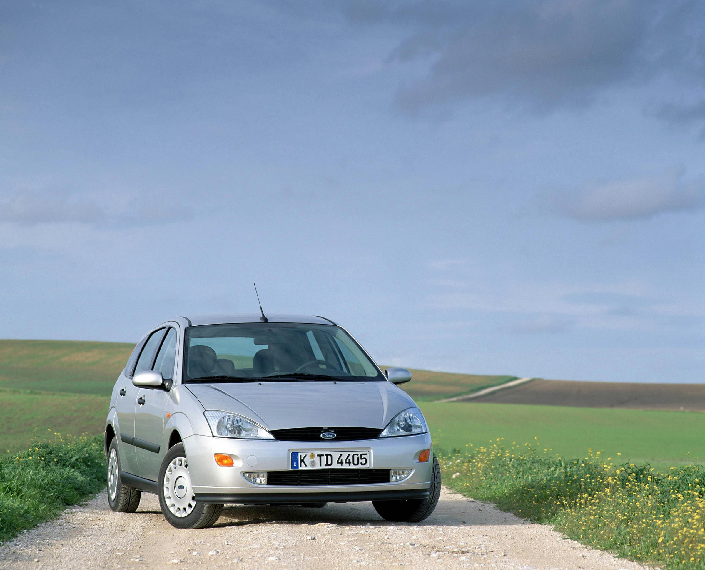 Silberner Ford Focus auf einem Kiesweg durch ländliche Felder unter bewölktem Himmel.