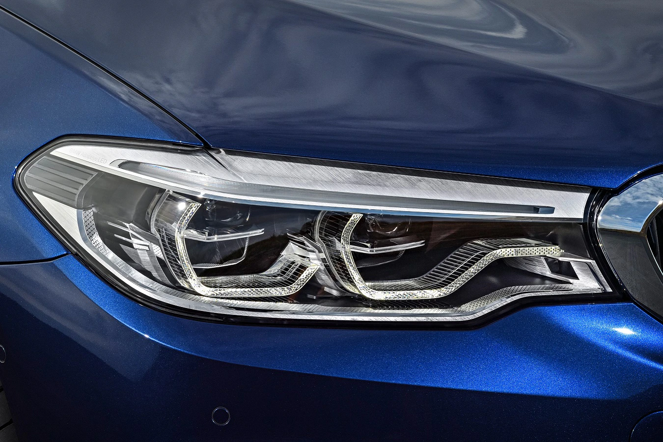 Nahaufnahme eines modernen Scheinwerfers eines blauen Autos mit klaren Linien und eleganten Details.