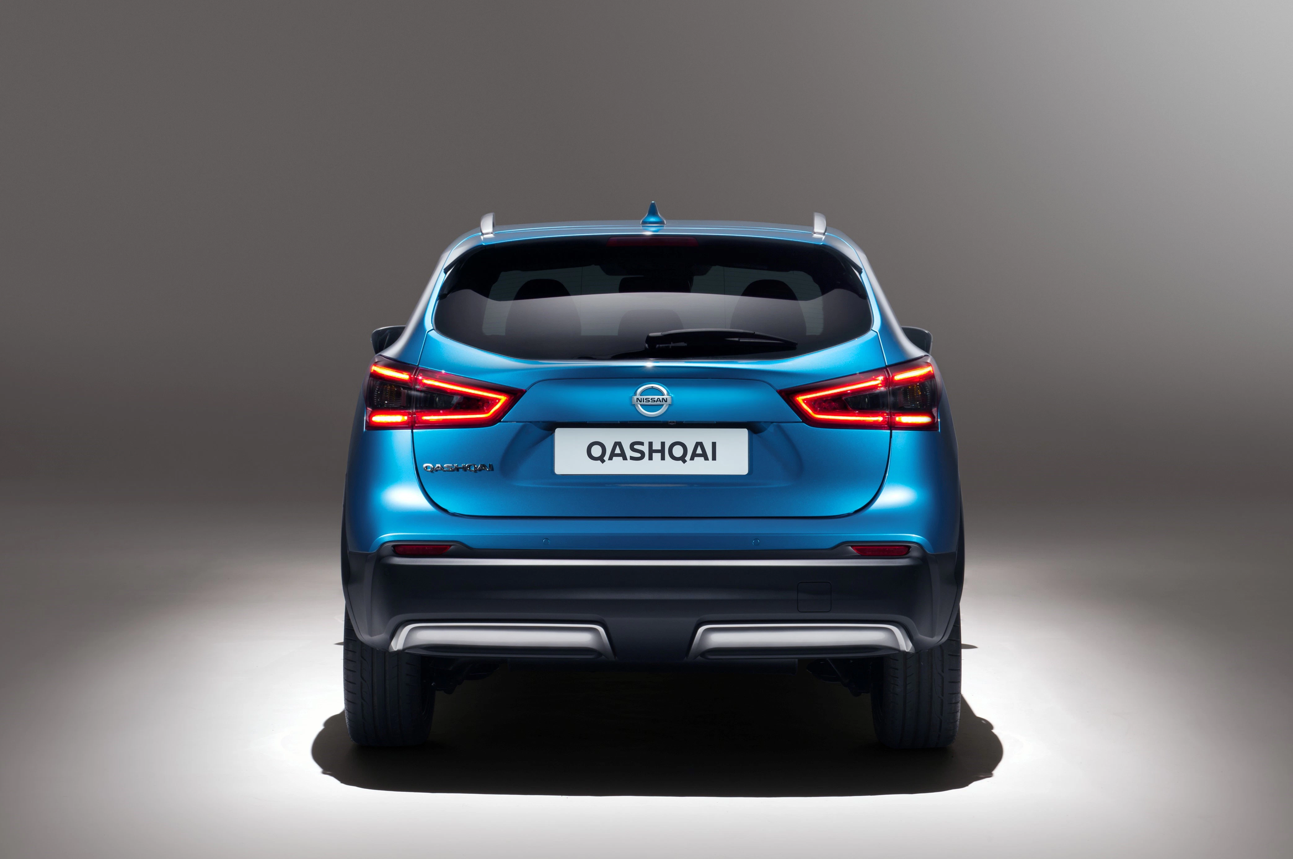 Rückansicht eines blauen Nissan Qashqai mit leuchtenden Rücklichtern auf grauem Hintergrund.