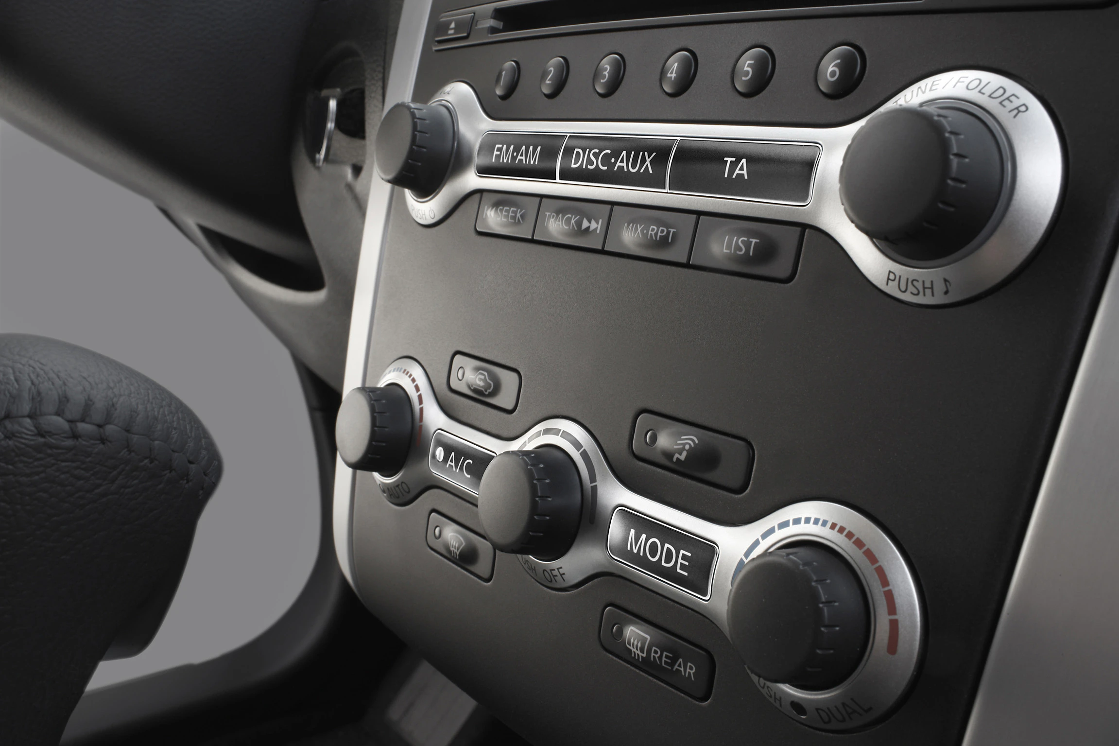Nahaufnahme eines modernen Autoarmaturenbretts mit diversen Drehknöpfen und Tasten für Radio und Klimaanlage.