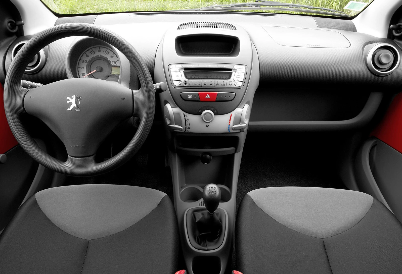 Innenraum eines Autos mit grauen Sitzen, Lenkrad, Armaturenbrett mit Radio und Lüftungsdüsen. Markensymbol auf dem Lenkrad.