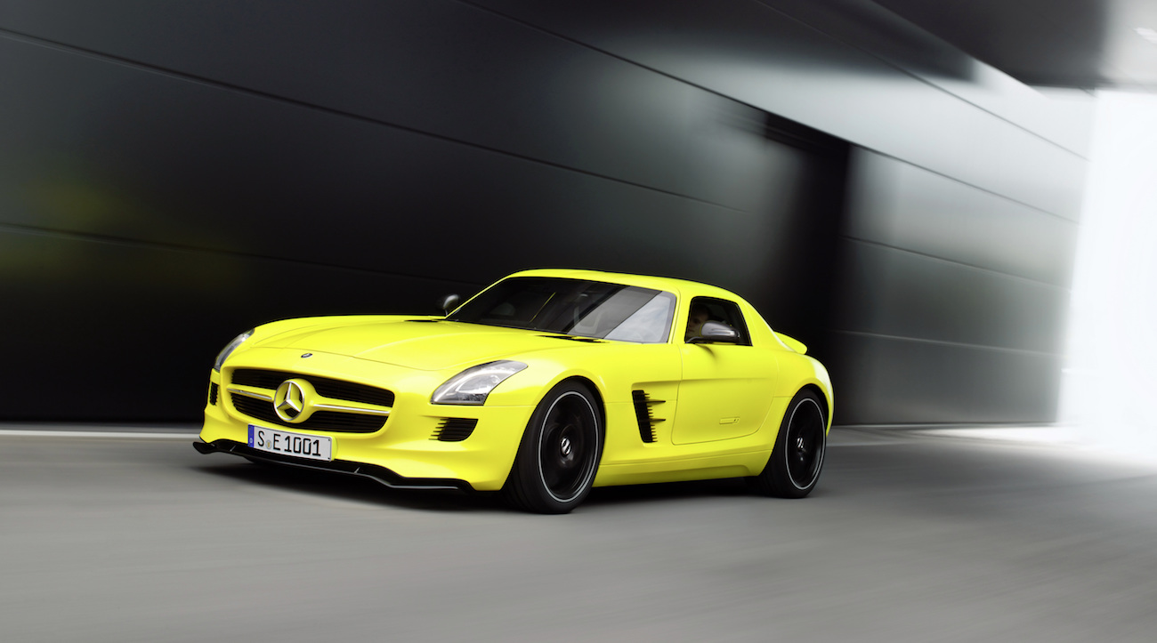 Gelber Mercedes-Benz SLS AMG fährt dynamisch durch einen modernen Tunnel mit verschwommenem Hintergrund.