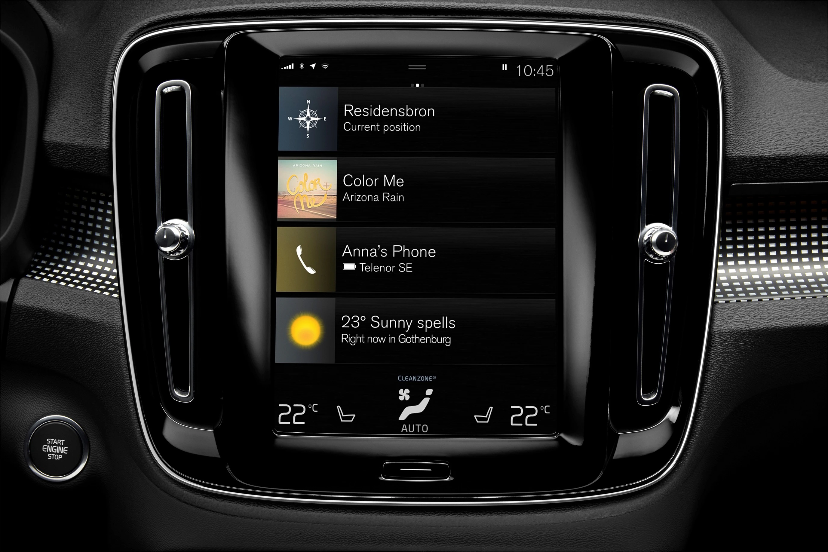 Nahaufnahme eines Autodisplays mit Navigation, Musiktitel, Telefonverbindung und Wetteranzeige. Steuerungsknöpfe darunter.
