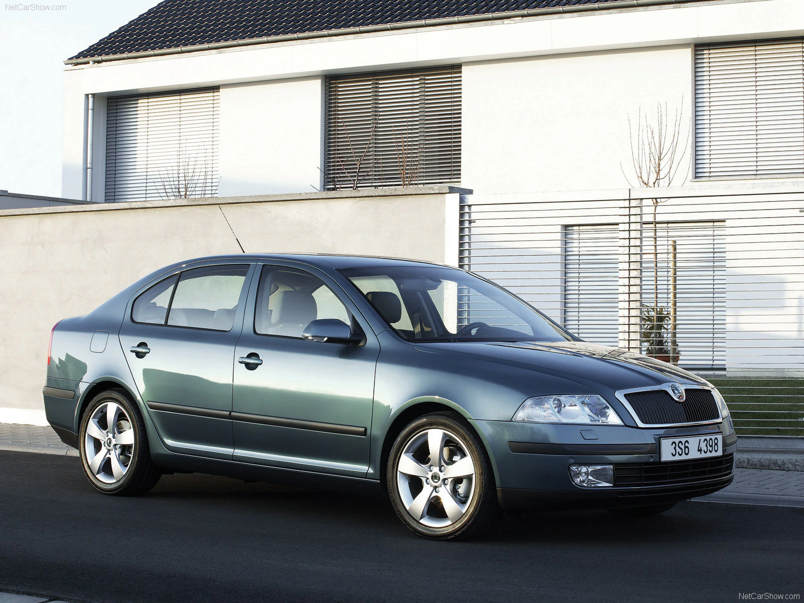 Silberner Škoda Octavia Limousine parkt vor einem modernen Haus mit Flachdach und Fensterläden.
