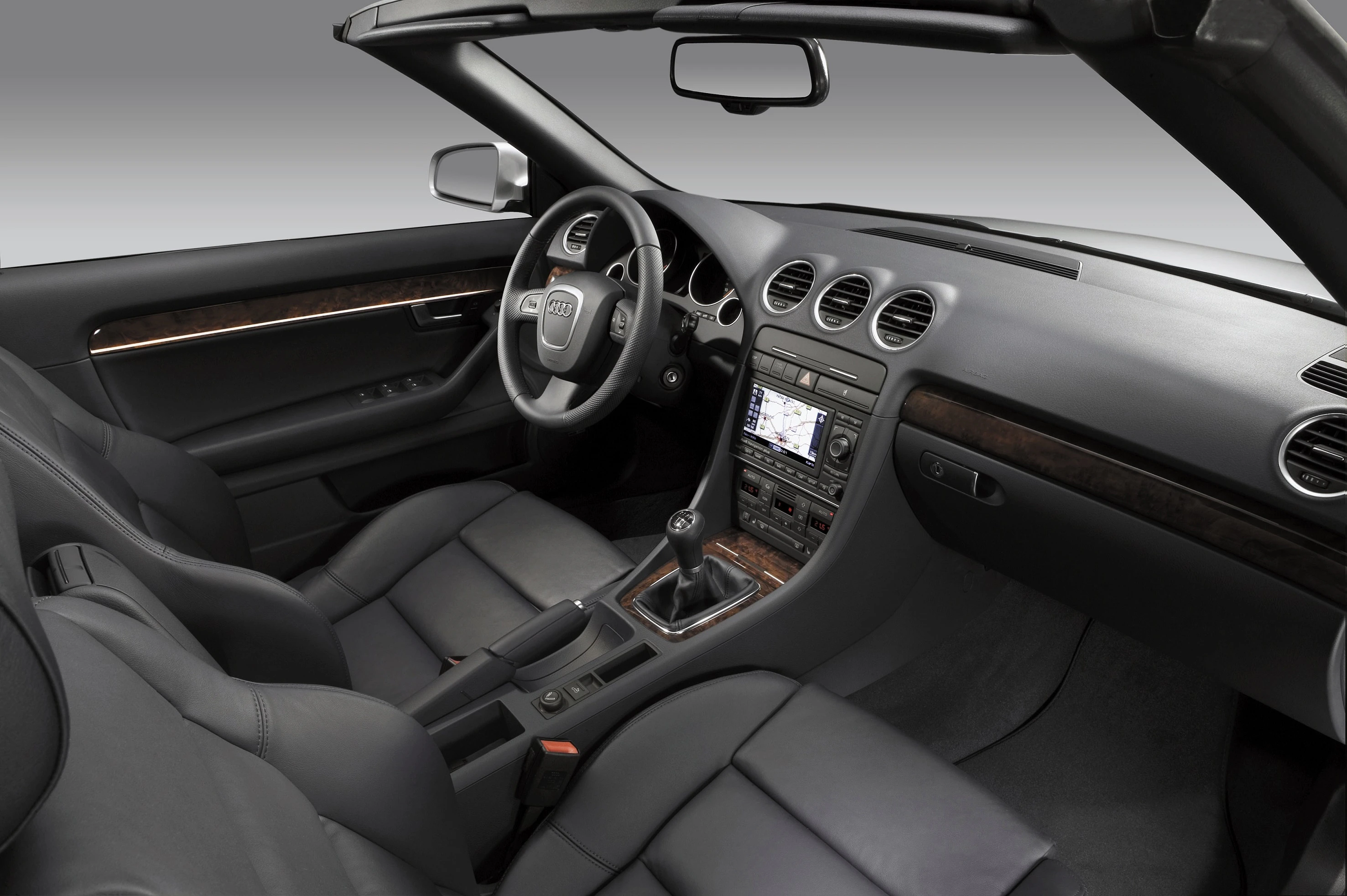 Innenraum eines eleganten, schwarzen Cabriolets mit Lederausstattung und modernem Armaturenbrett. Sicht auf Lenkrad und Mittelkonsole.