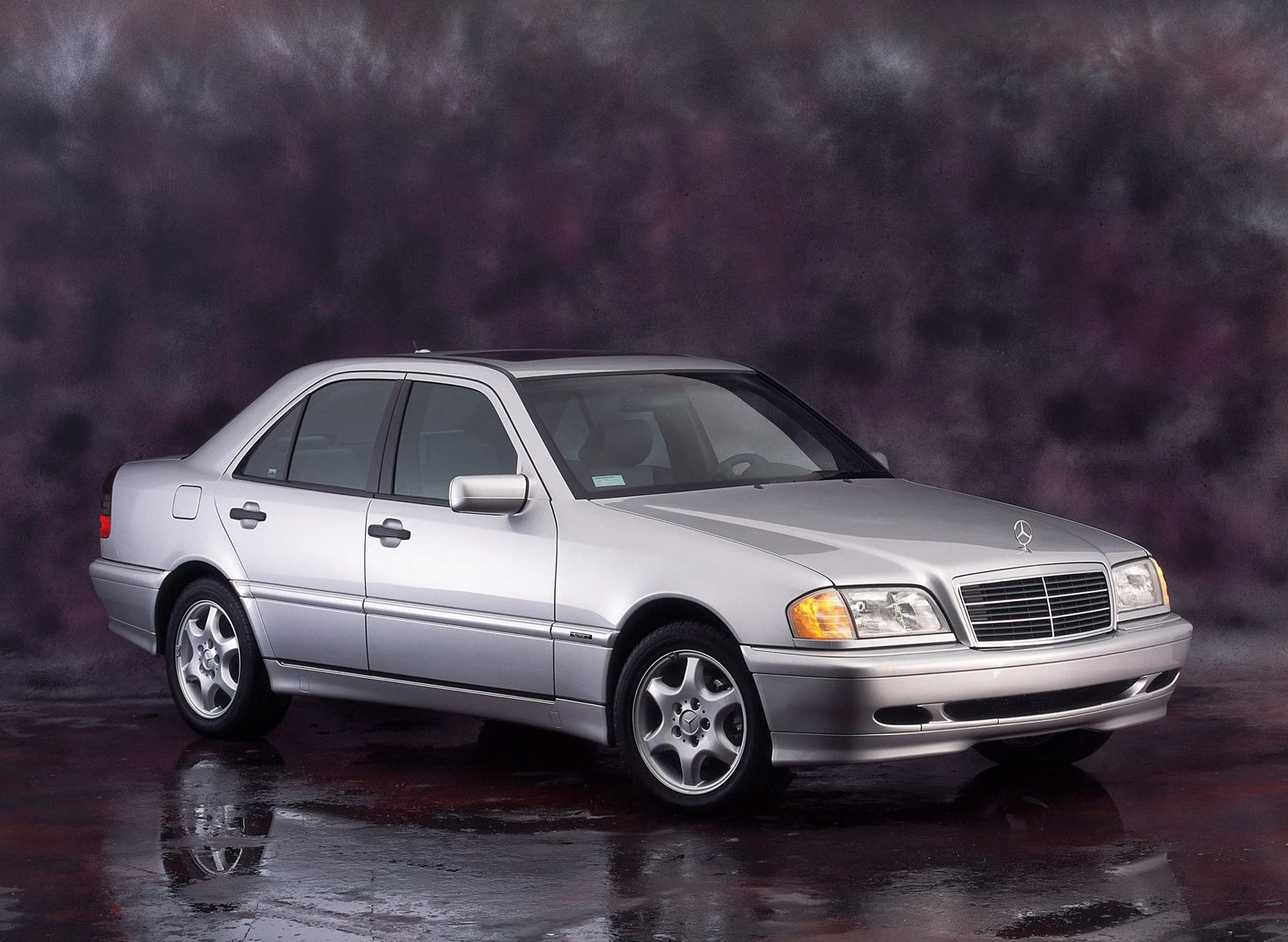Silberner Mercedes-Benz-Limousine vor dunklem, verschwommenem Hintergrund, seitlich aufgenommen mit Klarheit und Eleganz.