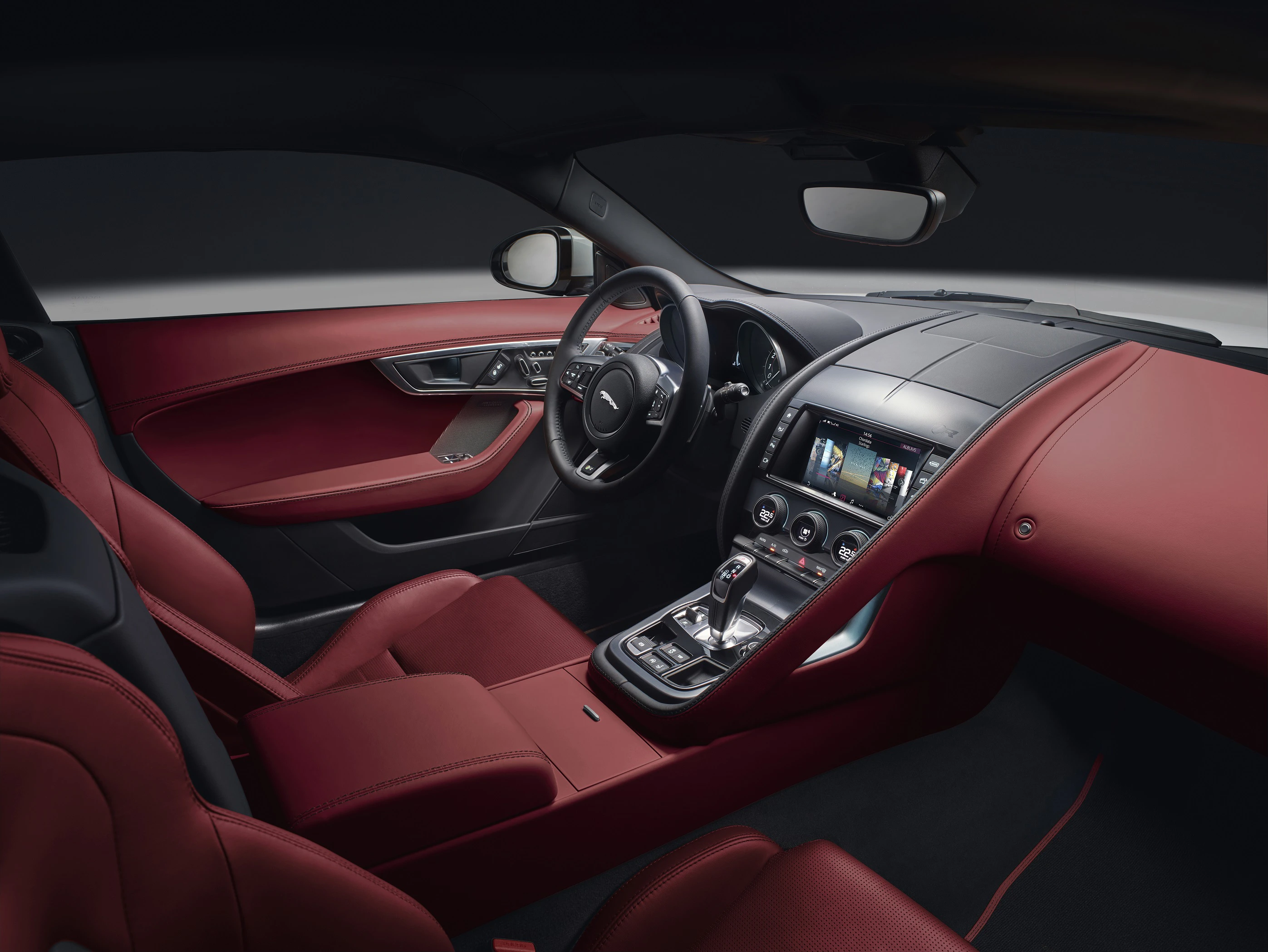 Innenraum eines modernen Autos mit roter Lederausstattung, eleganter Mittelkonsole, Lenkrad und integriertem Display.