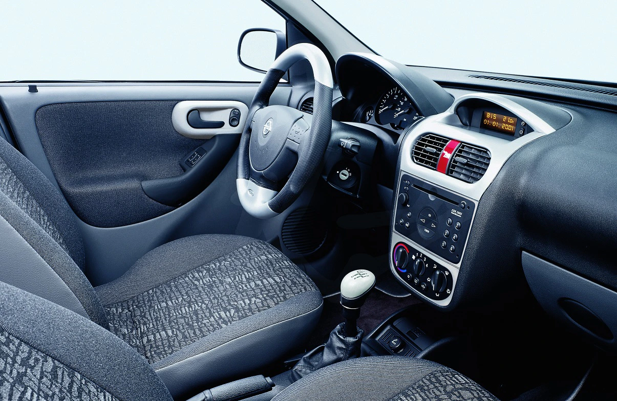 Innenraum eines Autos mit grauen Sitzen, Lenkrad, Schaltknüppel und Armaturenbrett mit Radio und Klimaanlagensteuerung.
