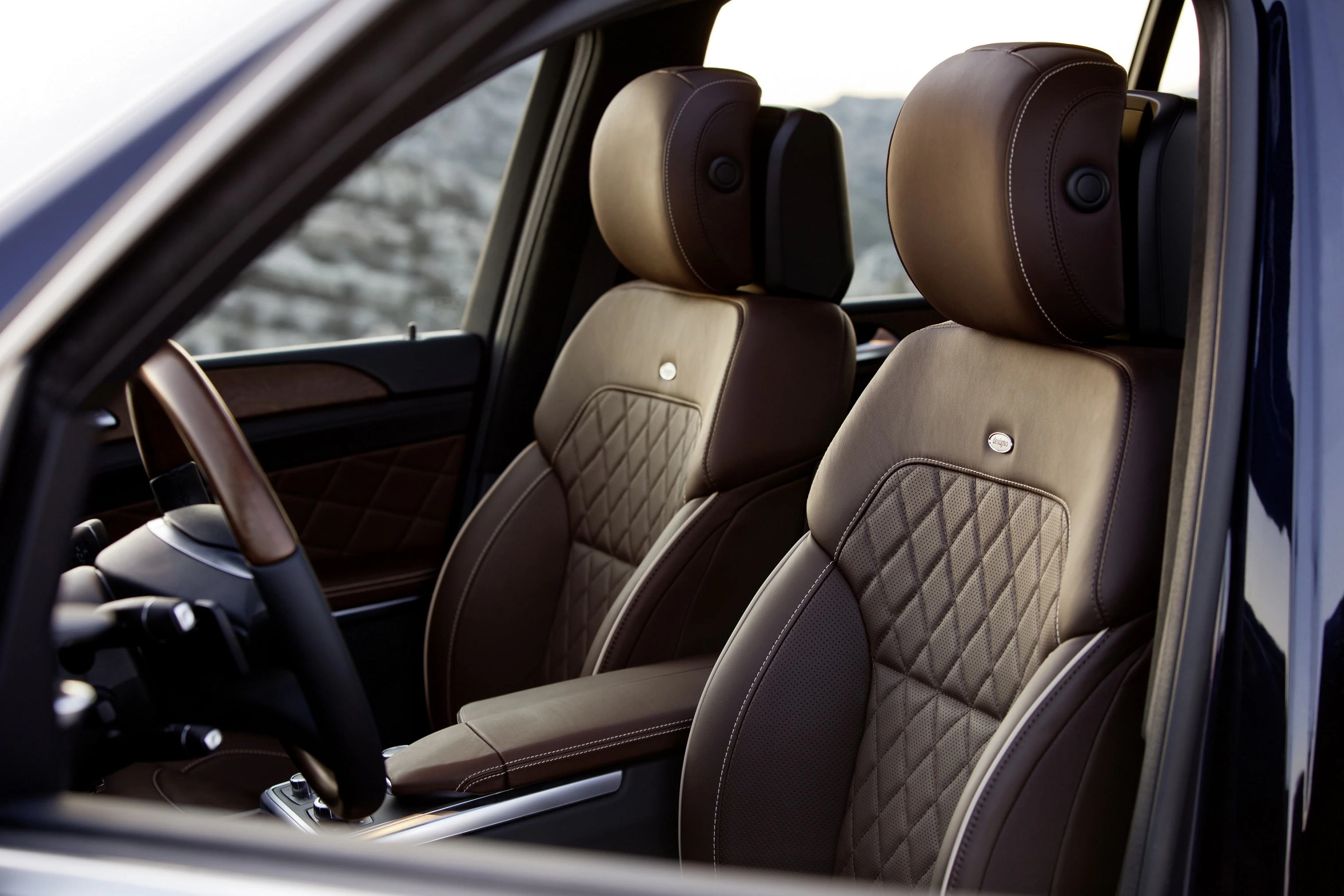 Lederbezogene Autositze mit gestepptem Muster in einem luxuriösen Auto, braune Töne, elegantes Design, Sicht auf Vorderseite und Armlehne.