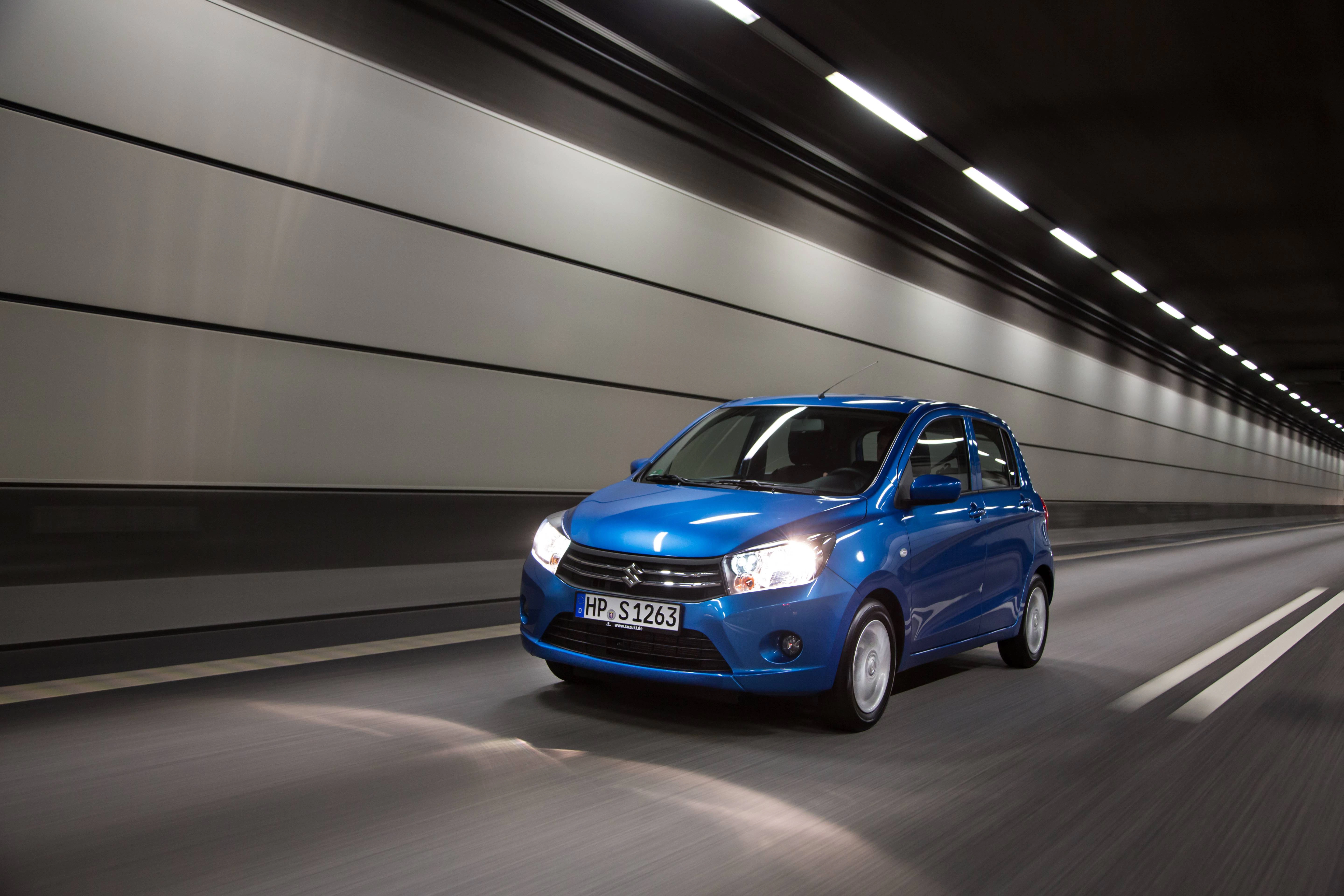 Blauer Kleinwagen fährt durch einen beleuchteten Tunnel. Die Umgebung zieht in verschwommenen Linien vorbei, was auf hohe Geschwindigkeit hinweist.