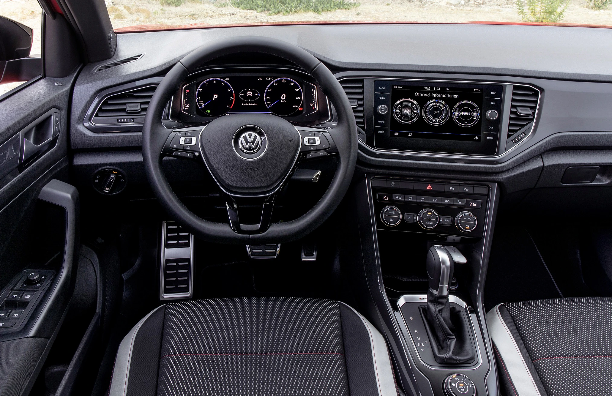 Innenraum eines Volkswagen mit Multifunktionslenkrad, Armaturenbrett, Touchscreen und Automatikwählhebel. Moderne Ausstattung in Schwarz.