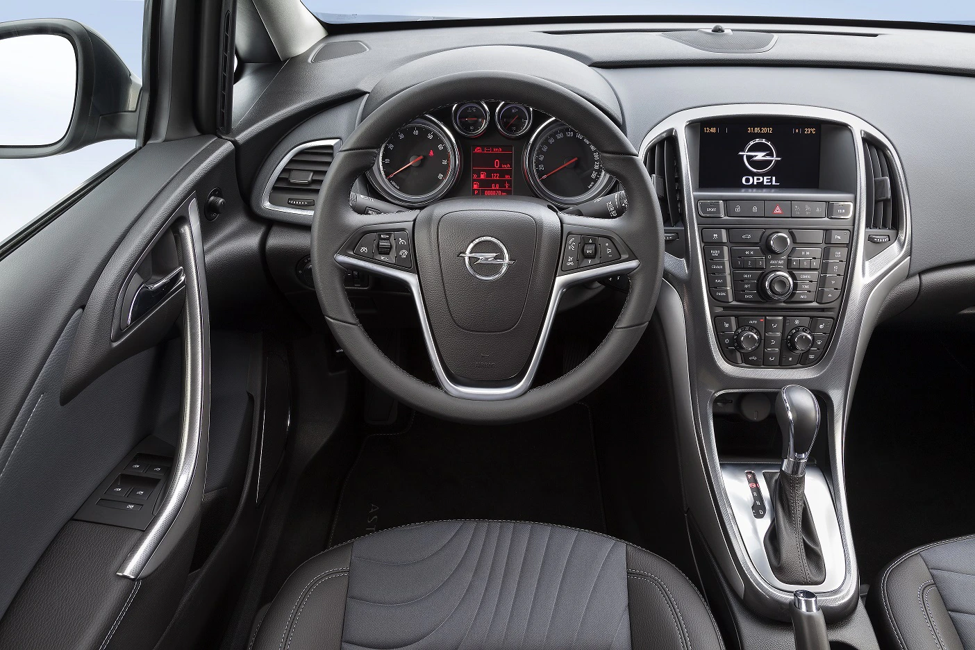 Innenansicht eines Opel-Autos mit Lenkrad, Armaturenbrett und Konsole. Sicht auf Anzeigen und Schalthebel, modernes Design.