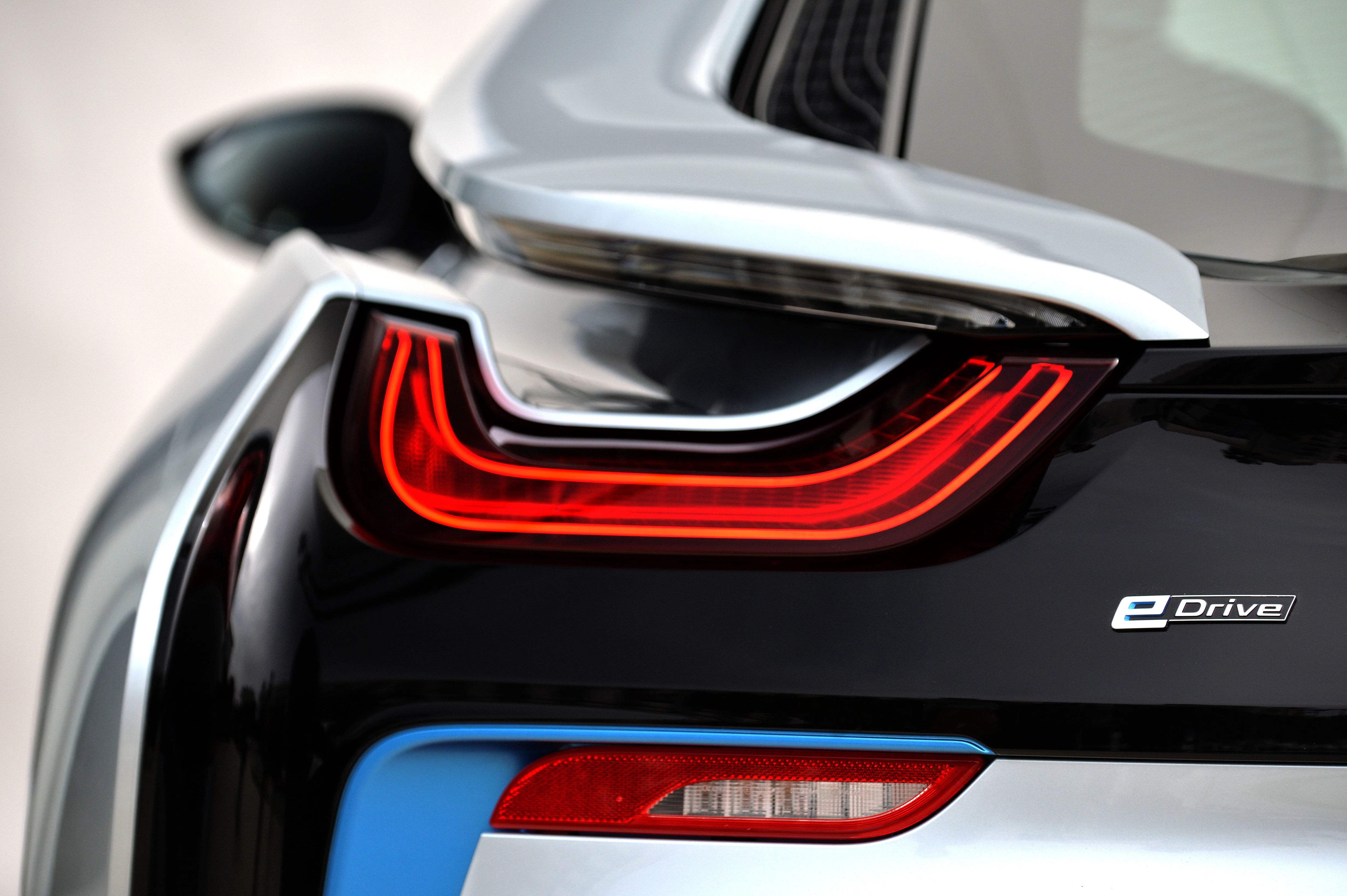 Rückansicht eines schwarzen Autos mit modernem, rot leuchtendem Rücklicht und „eDrive“-Emblem unter klarem Himmel.