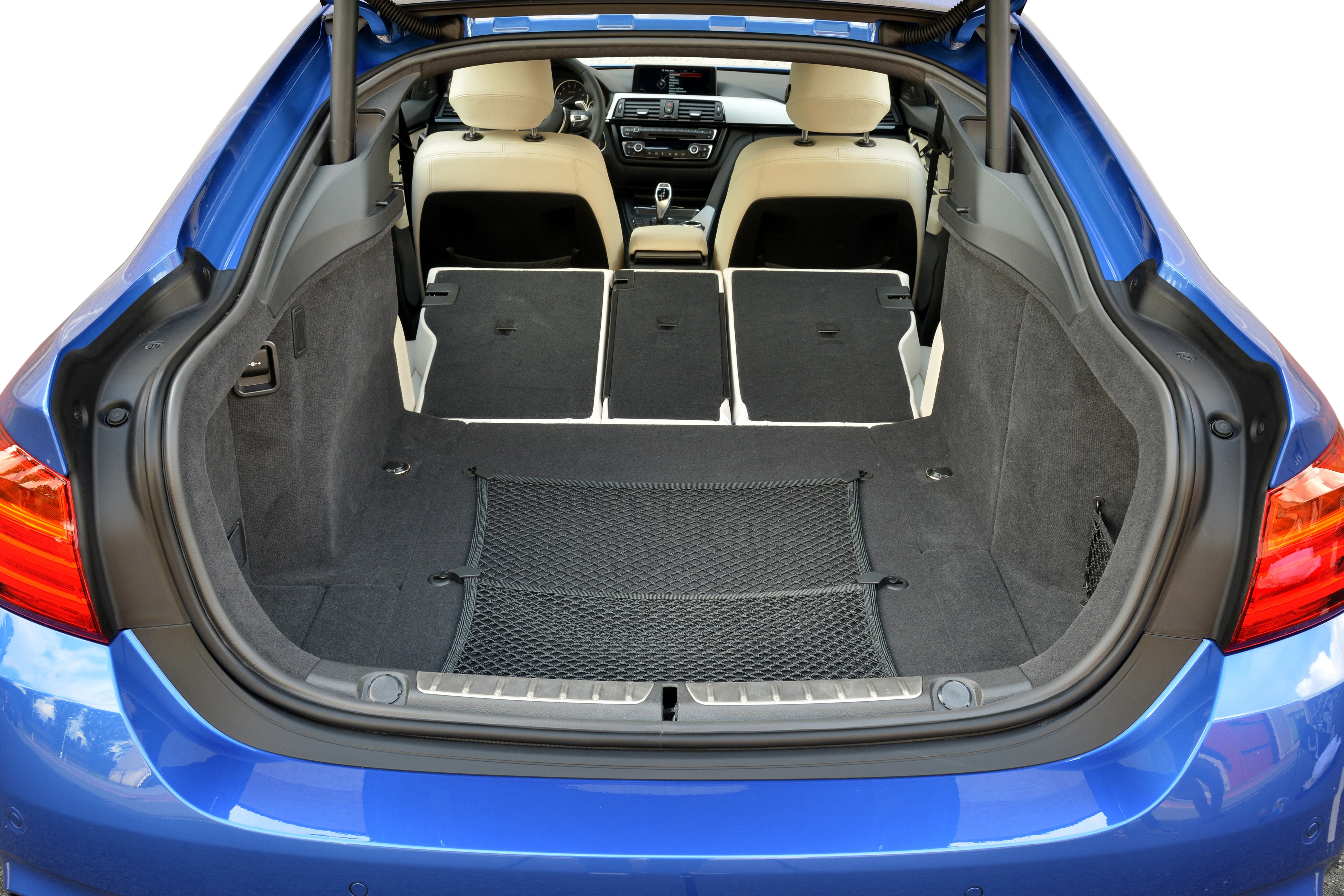 Blick in den Kofferraum eines blauen Autos mit umgeklappten Rücksitzen, die viel Ladefläche bieten. Beige Innenausstattung erkennbar.