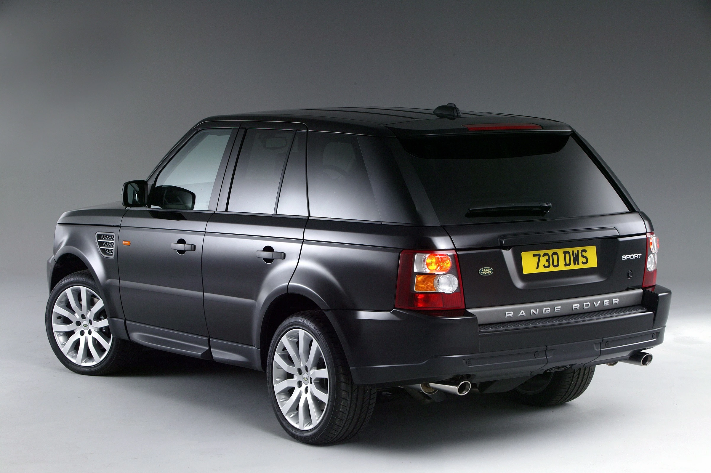 Schwarzer Range Rover Sport SUV, gesehen von hinten, auf grauem Hintergrund. Britisches Kennzeichen, silberne Felgen.