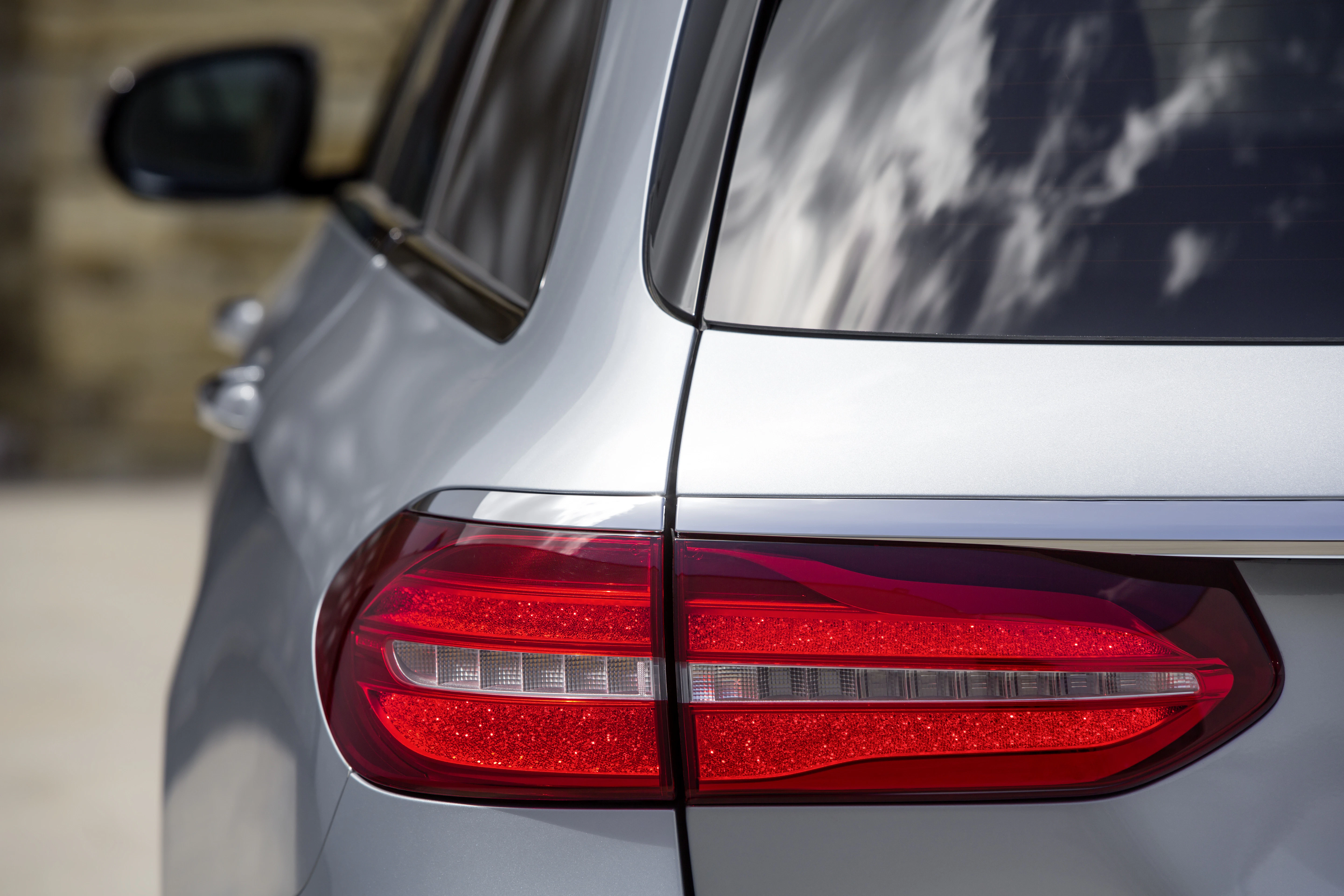 Rückansicht eines silbernen Autos mit leuchtenden roten Rücklichtern, die auf eine glatte, moderne Karosserie montiert sind.
