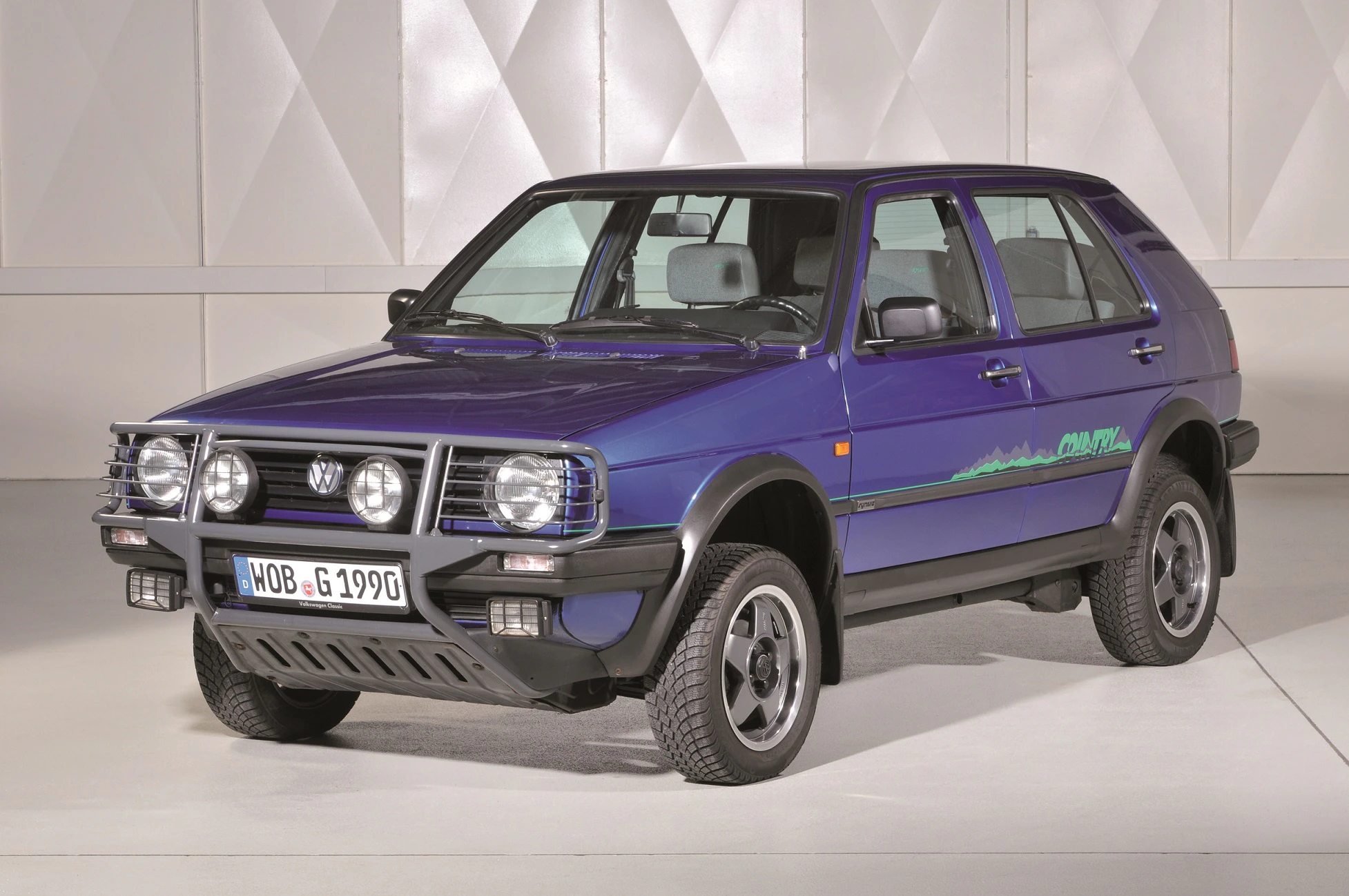 Lila Volkswagen Golf Country, ein Allradfahrzeug der 1990er Jahre, im Studio fotografiert, mit charakteristischer Frontstoßstange und Nebelscheinwerfern.