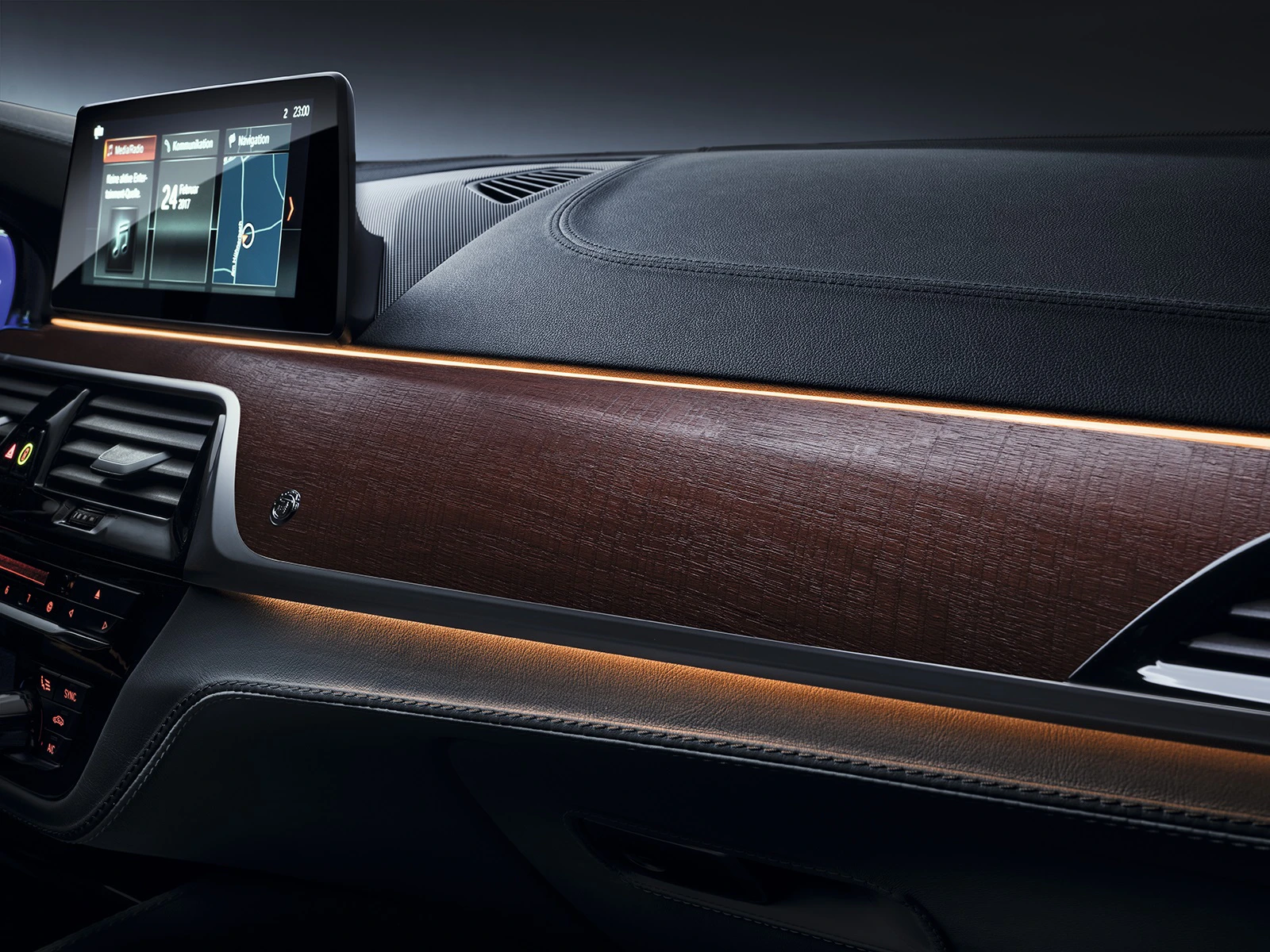Innenraum eines Autos mit moderner Holzverkleidung und Ambientebeleuchtung, digitales Display zeigt Navigationsinformationen.