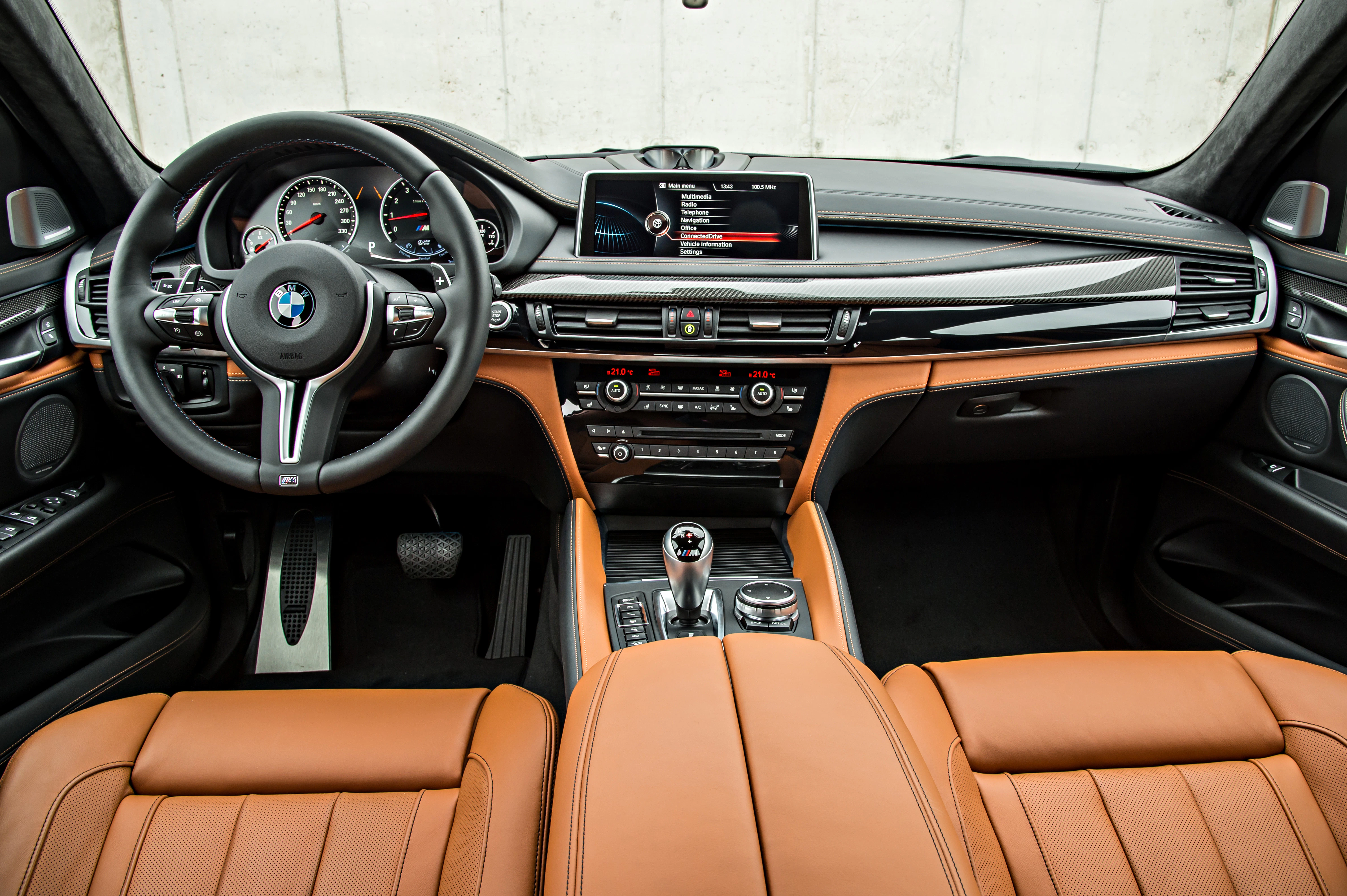 Innenraum eines Autos mit Leder-Innenausstattung, modernem Armaturenbrett, Multifunktionslenkrad und Display auf der Mittelkonsole.