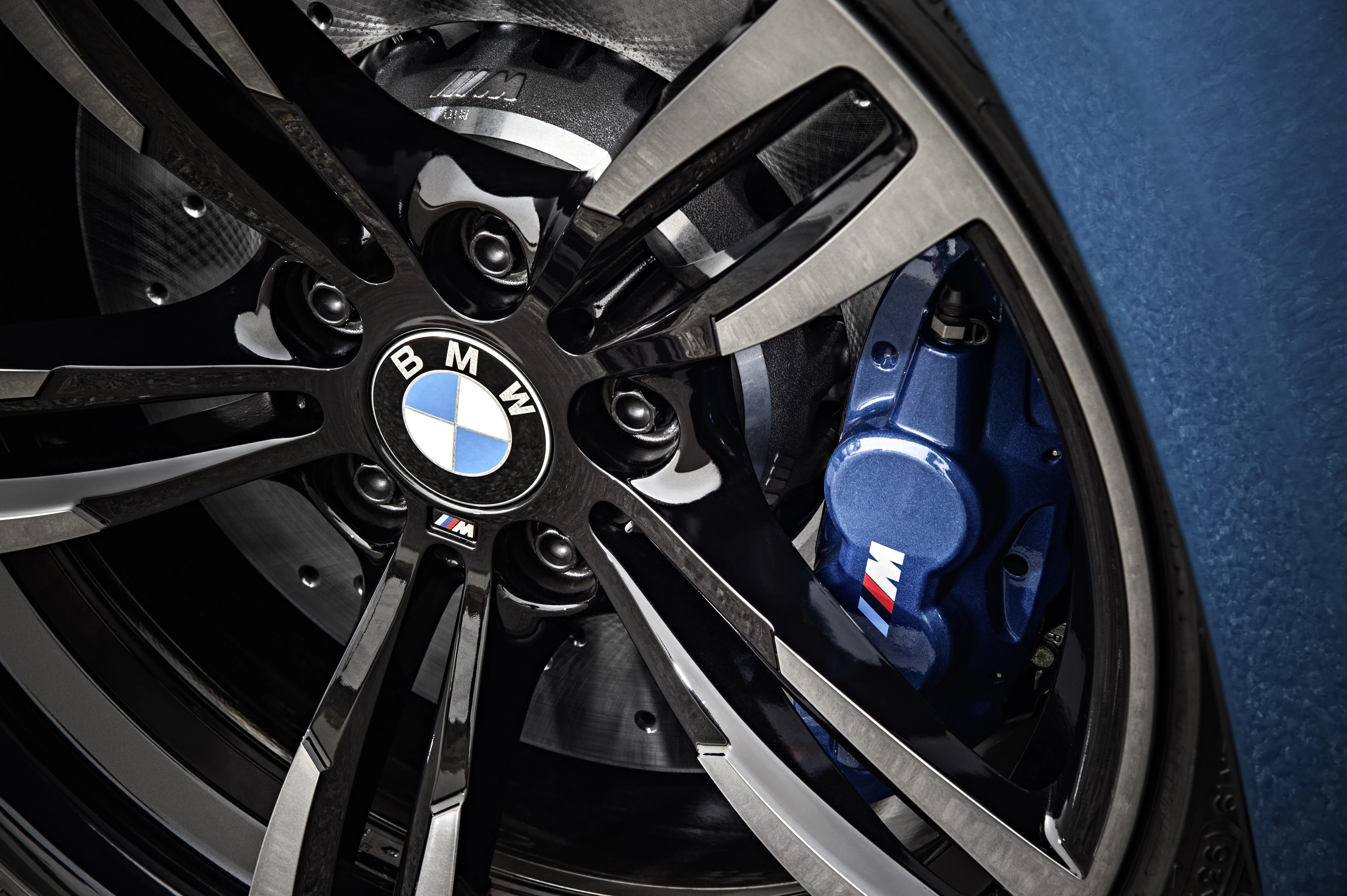 Nahaufnahme einer BMW Felge mit blauem Bremssattel. Das BMW-Logo ist auf der Felge zu sehen, umgeben von glänzenden Speichen.