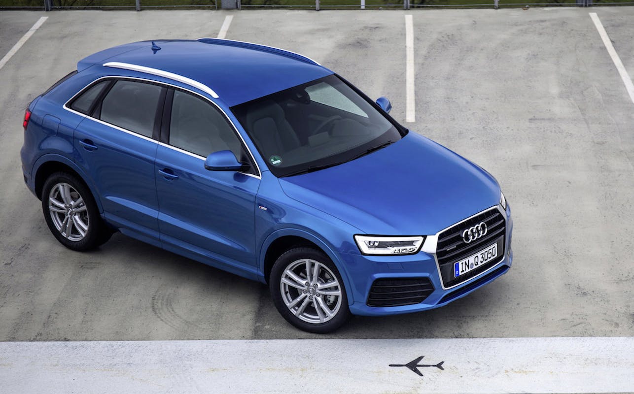 Blauer Audi Q3 auf einem leeren, markierten Parkplatz fotografiert, mit Blick von oben auf das Fahrzeug.