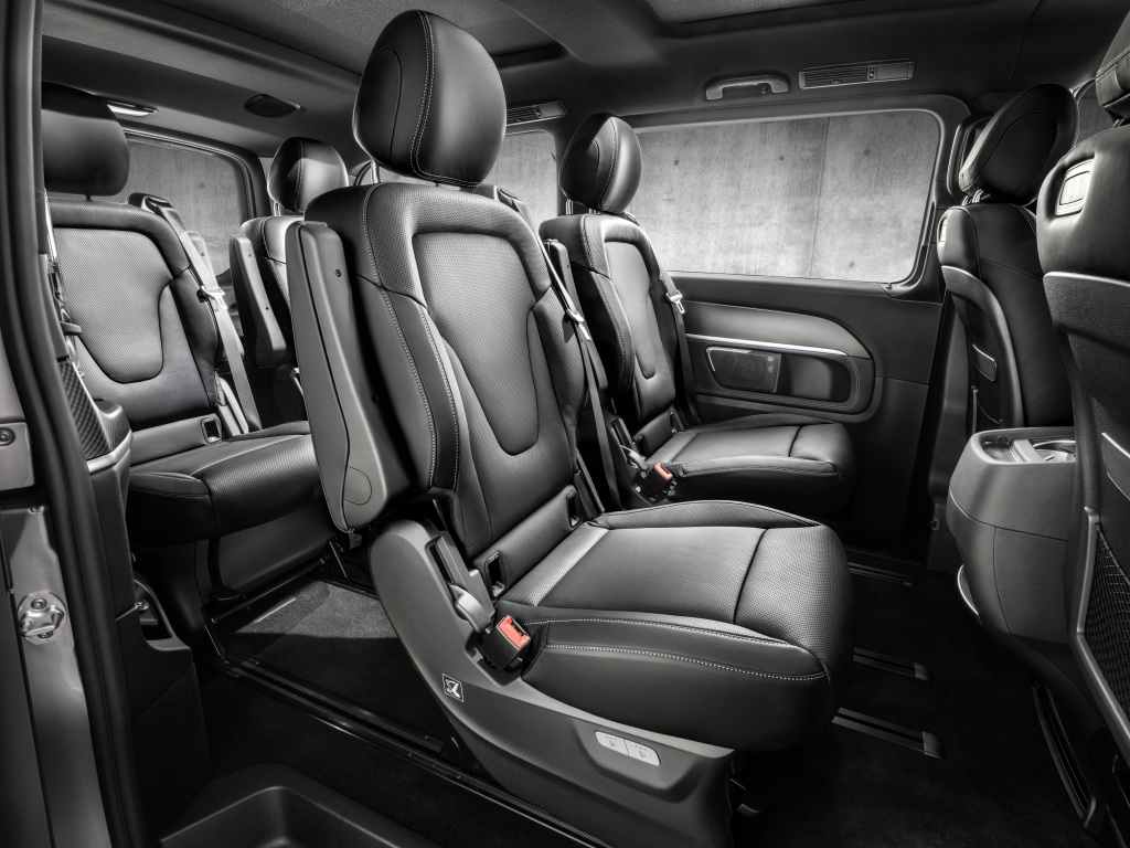 Innenansicht eines modernen Fahrzeugs mit drei Reihen aus schwarzen Ledersitzen, die geräumig und komfortabel wirken.