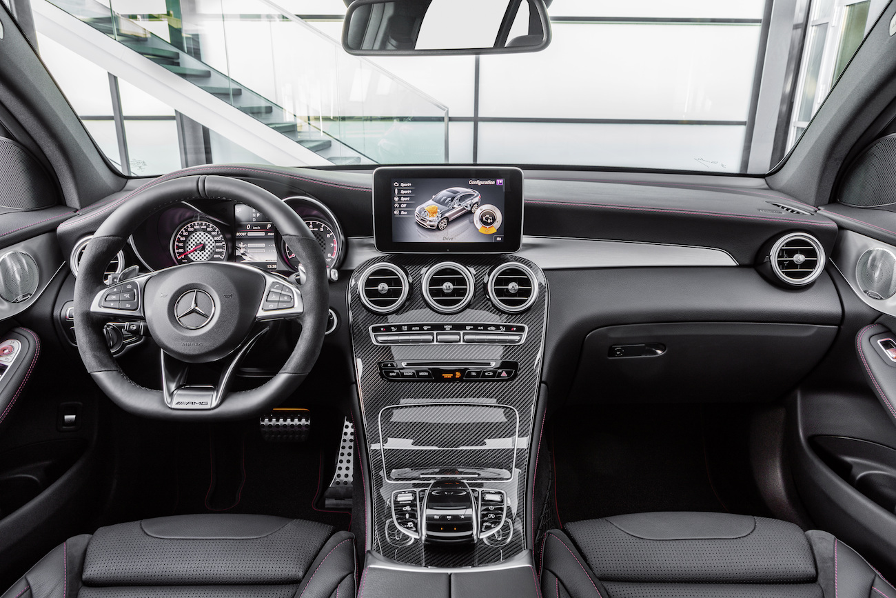Innenraum eines modernen Autos mit Lenkrad, Touchscreen-Display und Mittelkonsole in edlem Design. Mercedes-Benz Logo am Lenkrad.