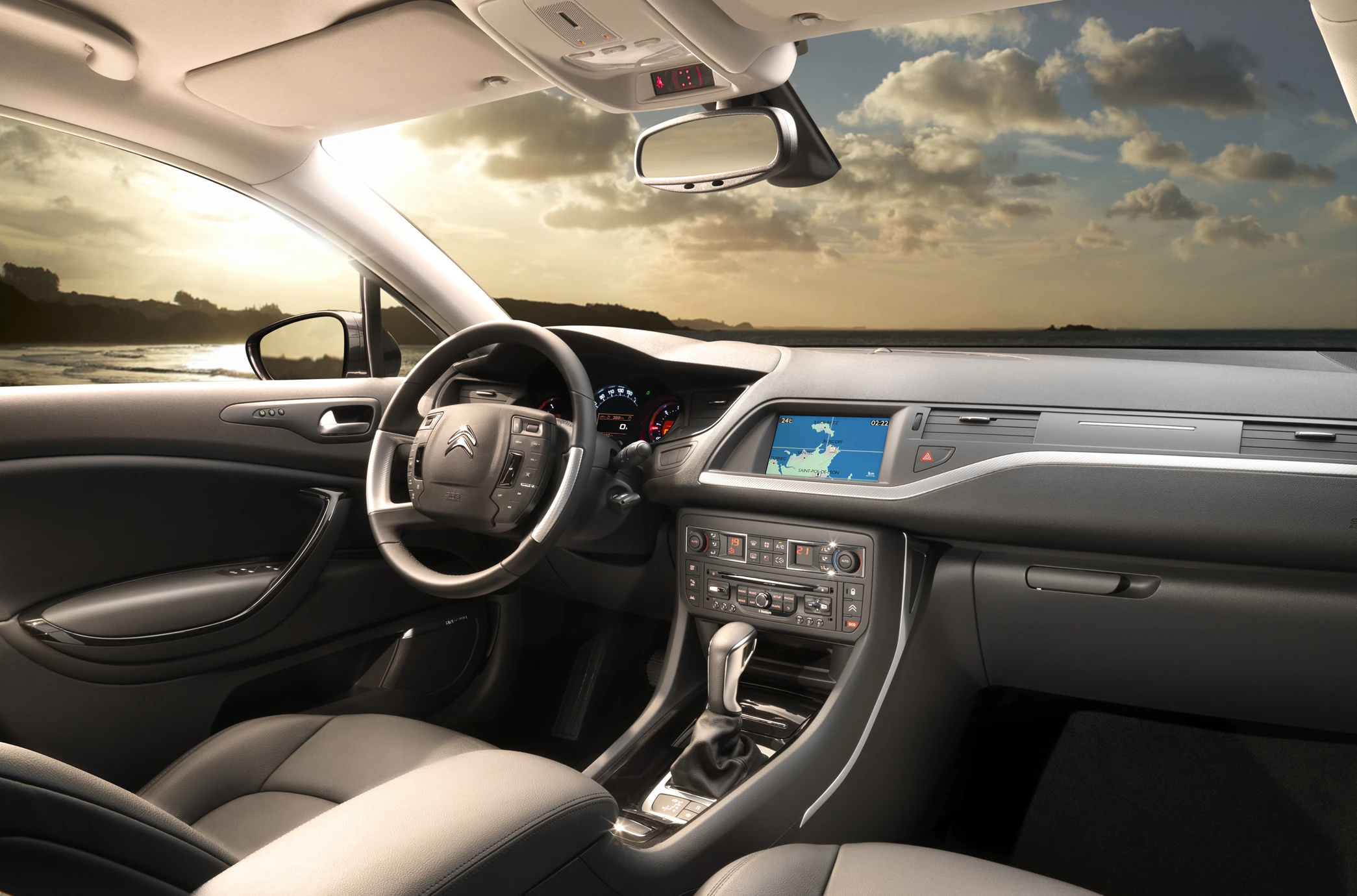 Innenraum eines Autos mit modernem Design, grauen Ledersitzen und integriertem Navigationssystem, Blick auf das Lenkrad und das Armaturenbrett.