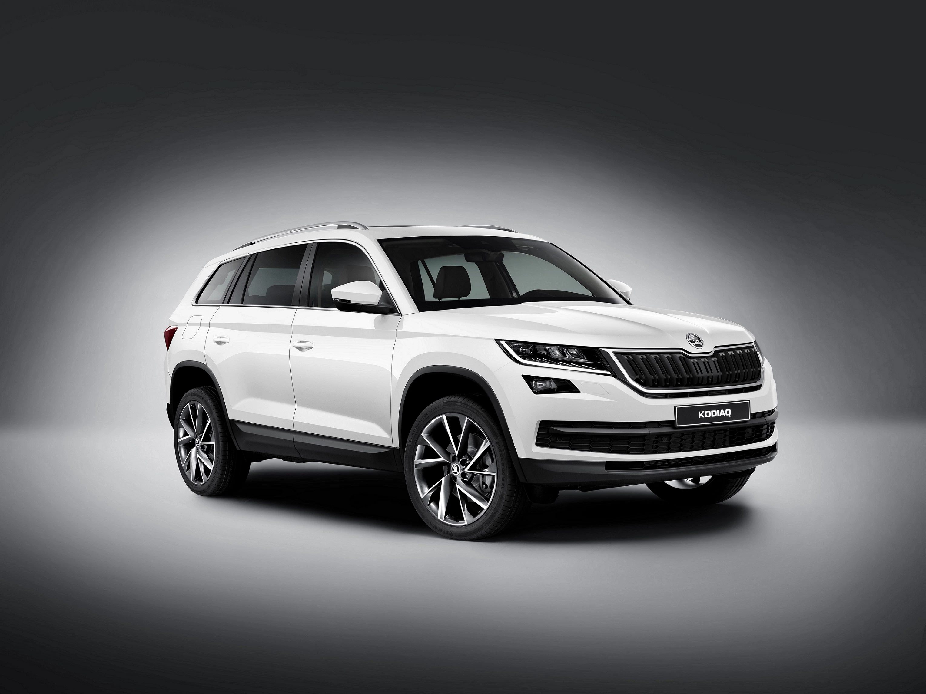 Weißer SUV mit glänzenden Details steht vor grauem Hintergrund auf einem Podest. Frontansicht zeigt markantes Design und größere Felgen.