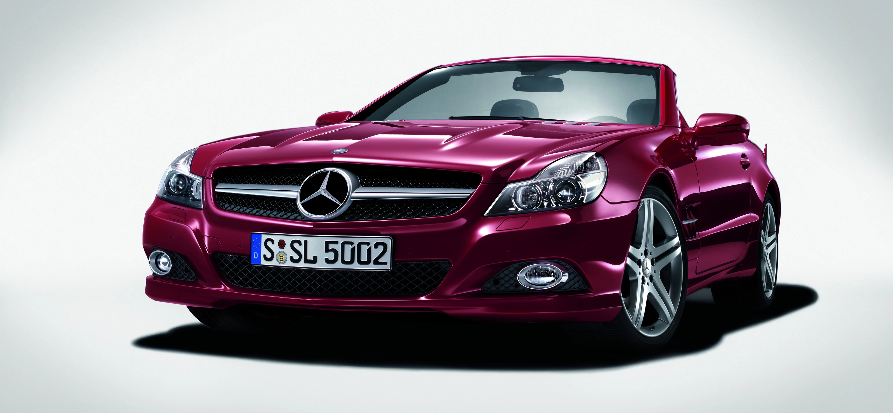 Roter Mercedes-Benz Cabrio von schräg vorne, auf weißem Hintergrund. Vorderansicht mit Nummernschild "S-SL 5002", glänzender Lack und Sportfelgen.